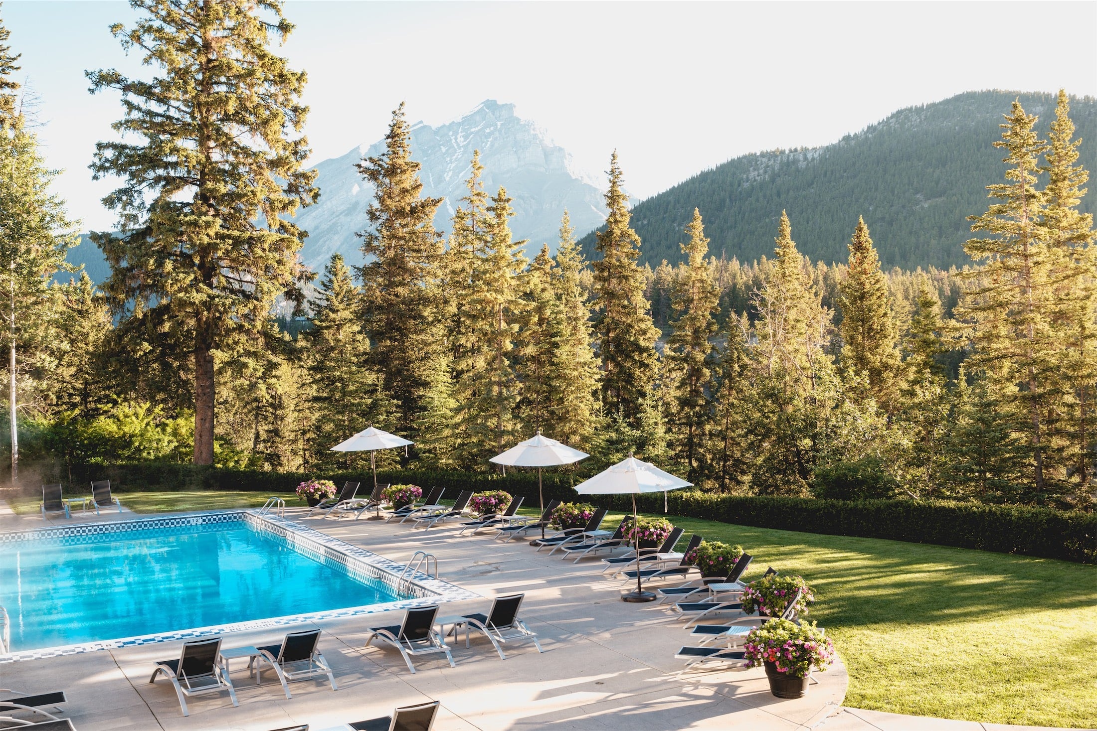 Outdoor swimming pool with forest and mountain backdrop at Fairmont Banff Springs, Banff, Canada