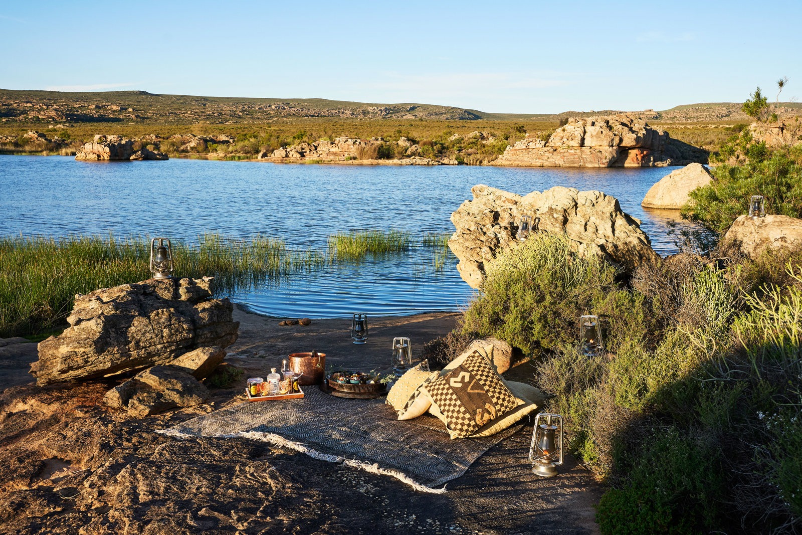 Rustic seats beside a lake and rocky shoreline, Bushmans Kloof, Cederberg Mountains, Western Cape, South Africa