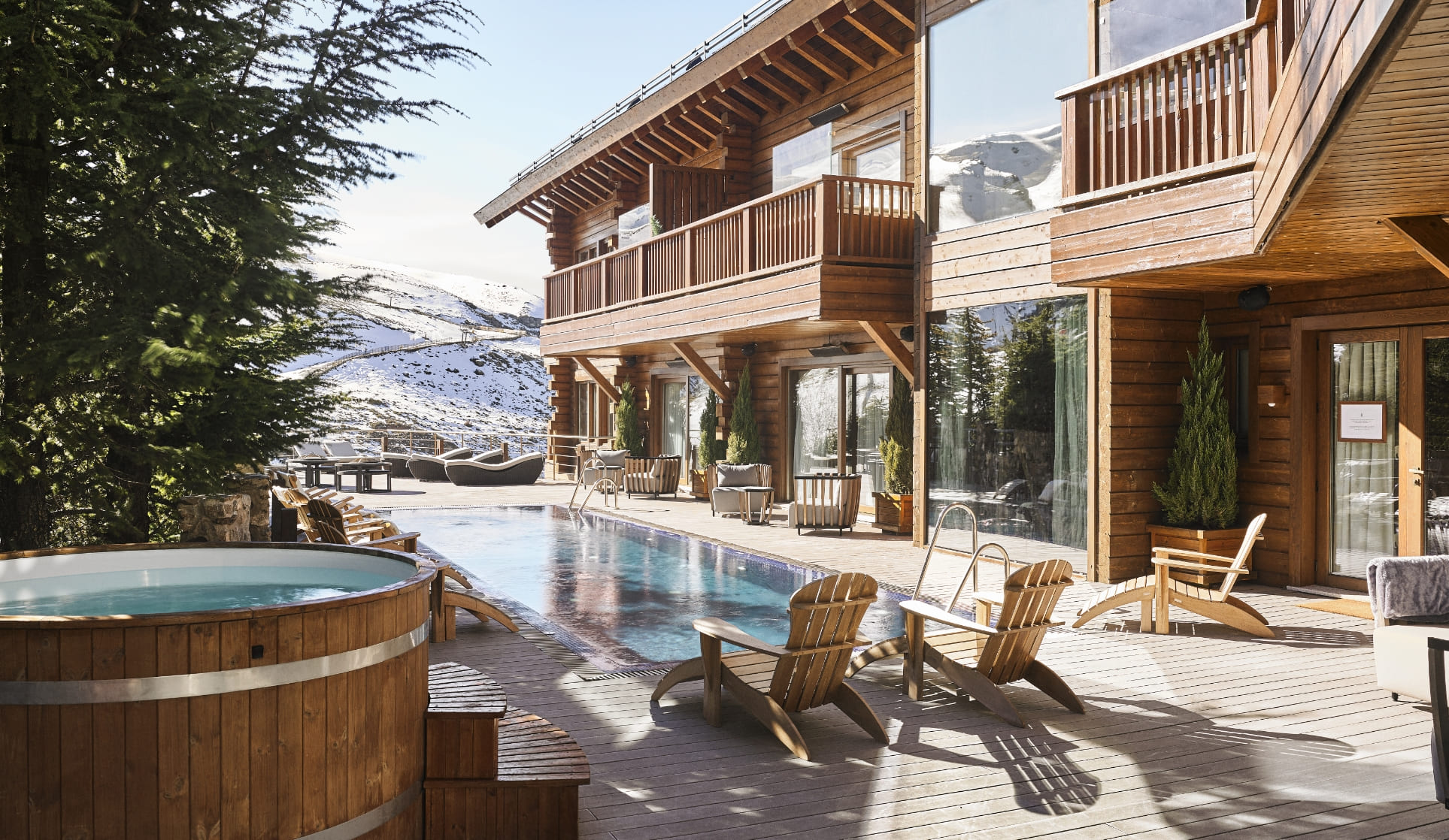 Timber lodge beside an outdoor pool and hot tub at El Lodge, Sierra Nevada, Spain