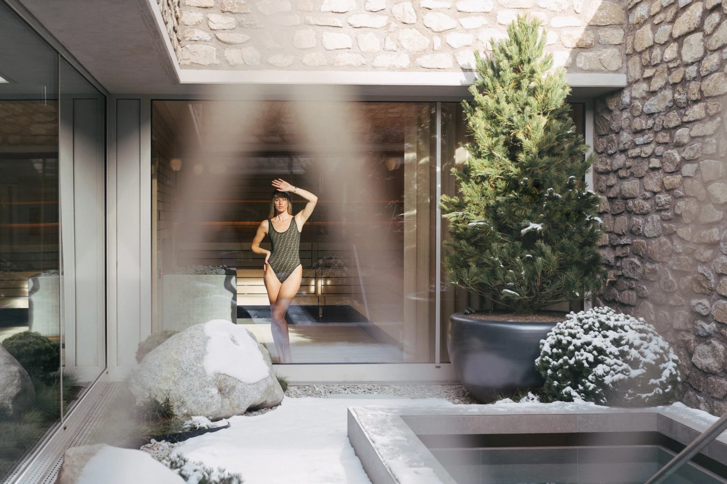 Guest beside the outdoor plunge pool in a stone-walled courtyard, Suvretta House, St. Moritz, Switzerland
