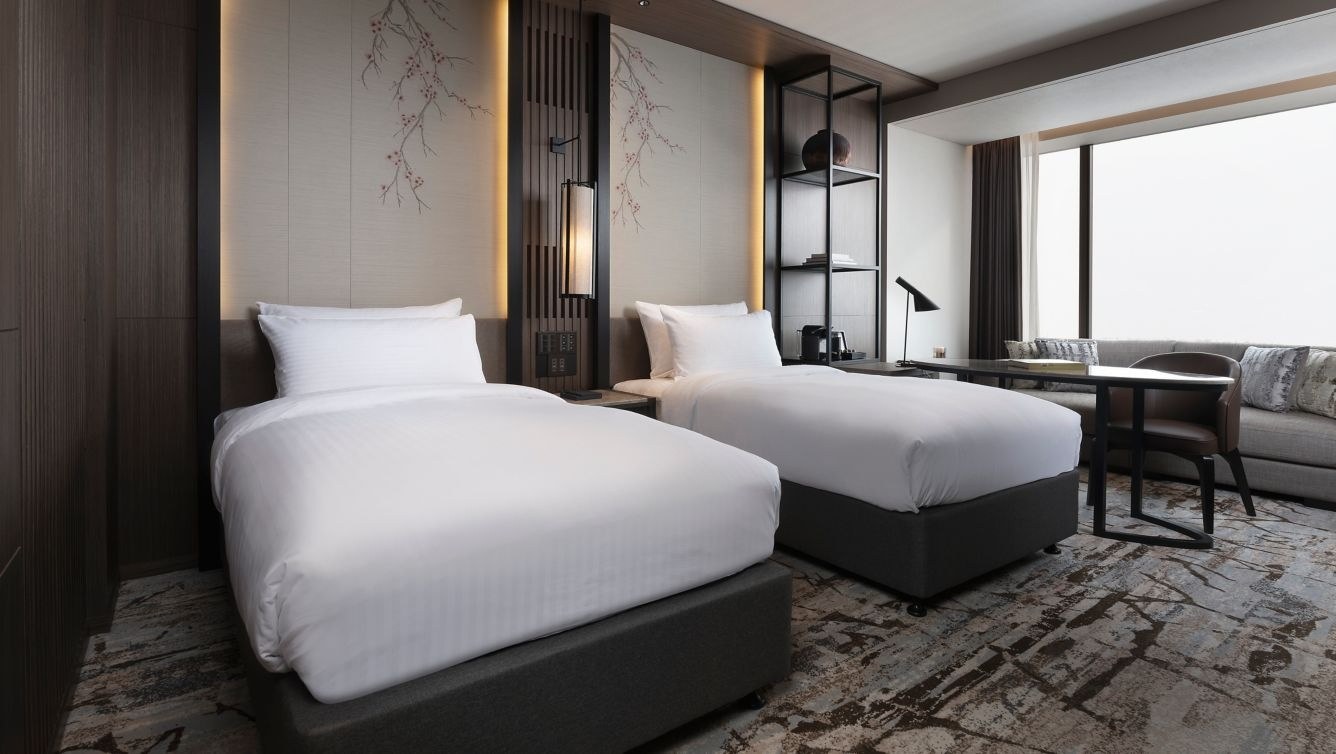 Twin-bed guest room with dark wood paneling, bedside lamps and a large window, Higashiyama Niseko Village, a Ritz-Carlton Reserve