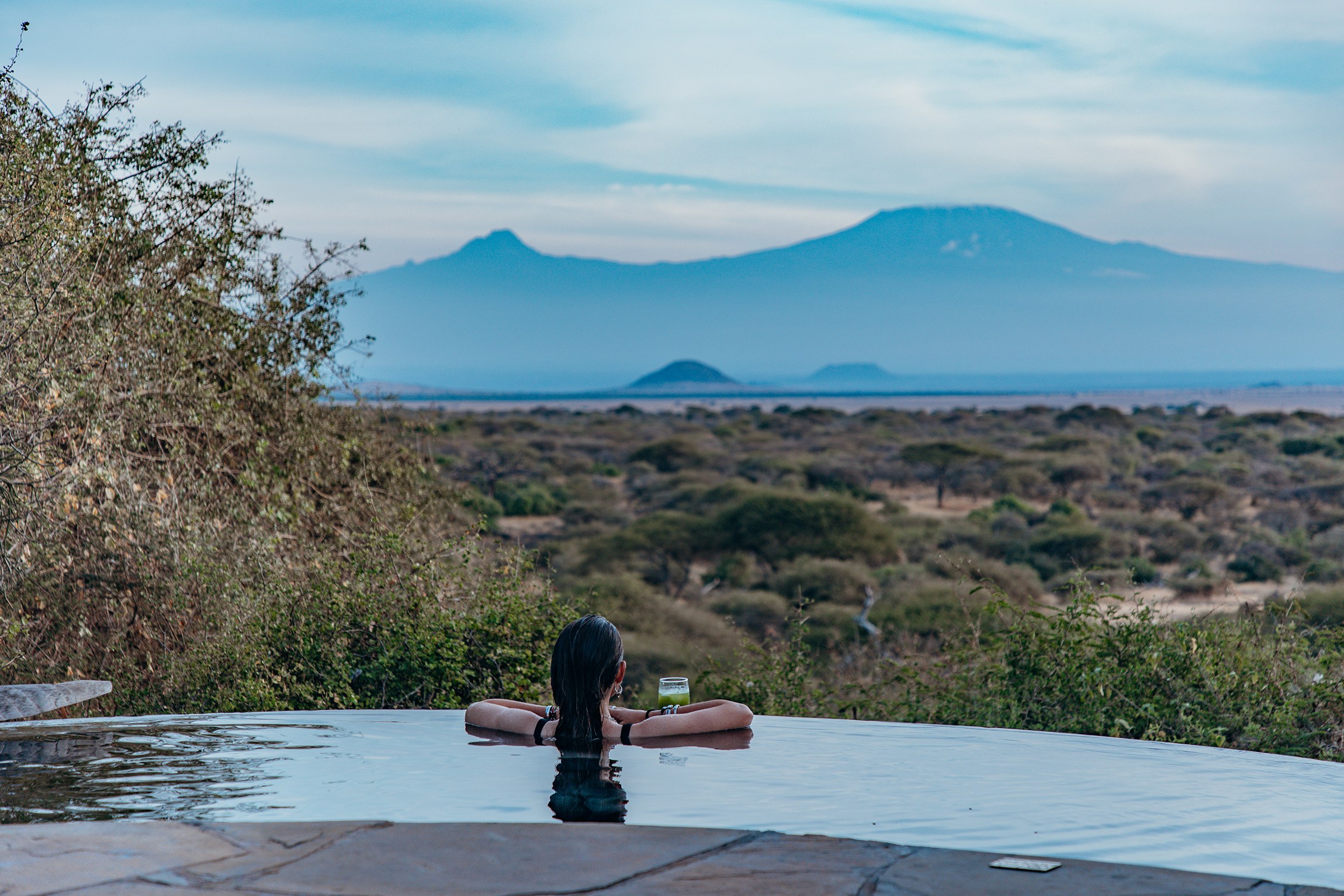 Swimmer in an infinity-edge pool with distant mountain views at Ol Donyo Lodge.