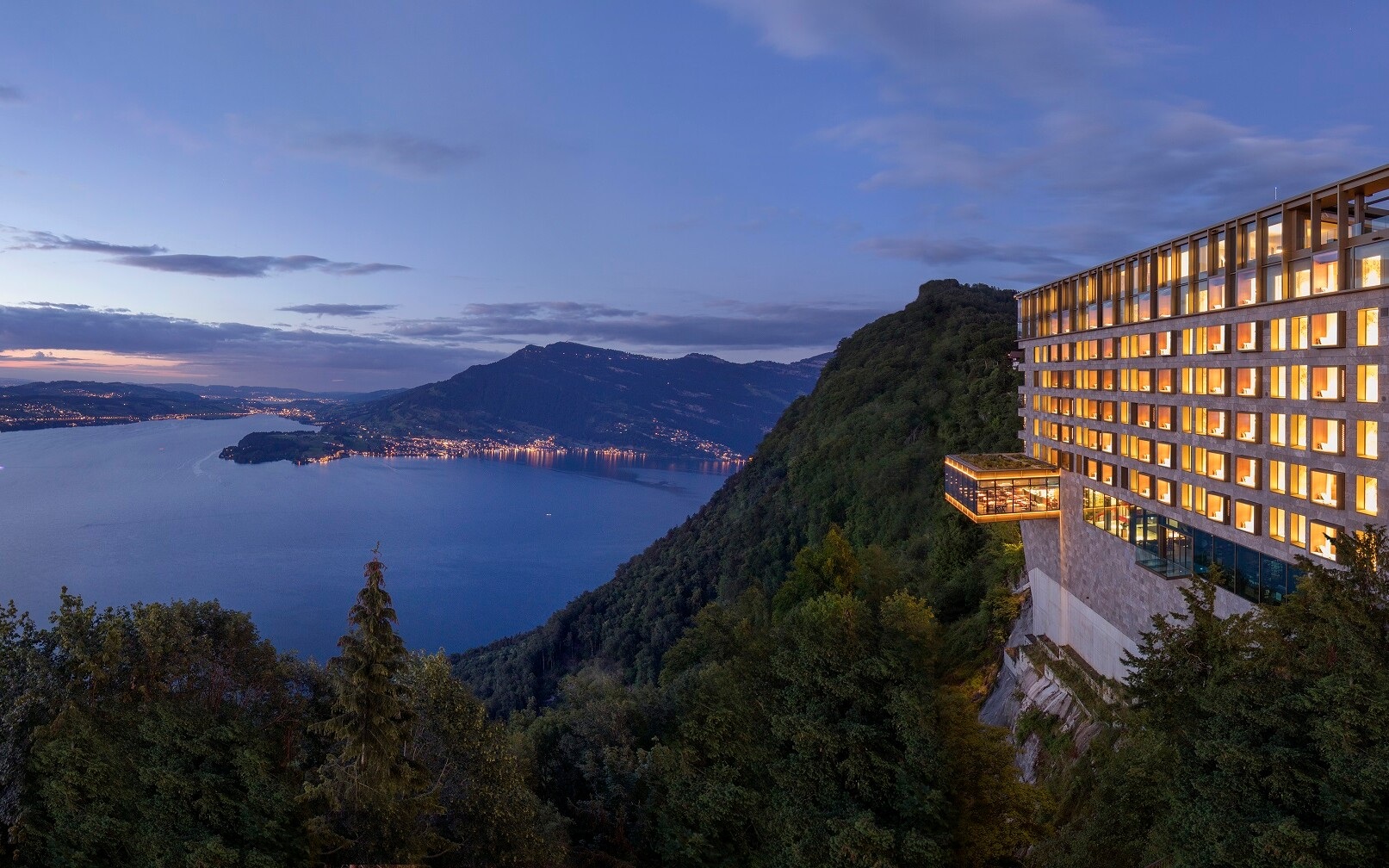 Hotel building on cliff above Lake Lucerne at dusk at Bürgenstock Resort, Lake Lucerne, Switzerland