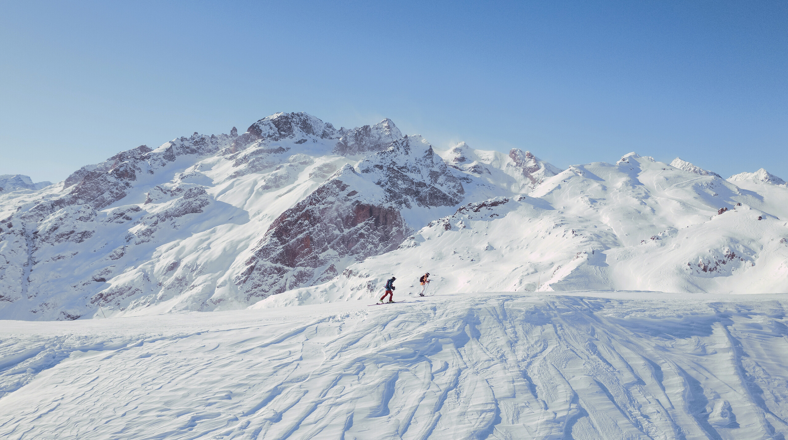 Skiers on a groomed snowy slope beneath the jagged peaks of the Tignes–Val d’Isère ski area, Club Med Tignes