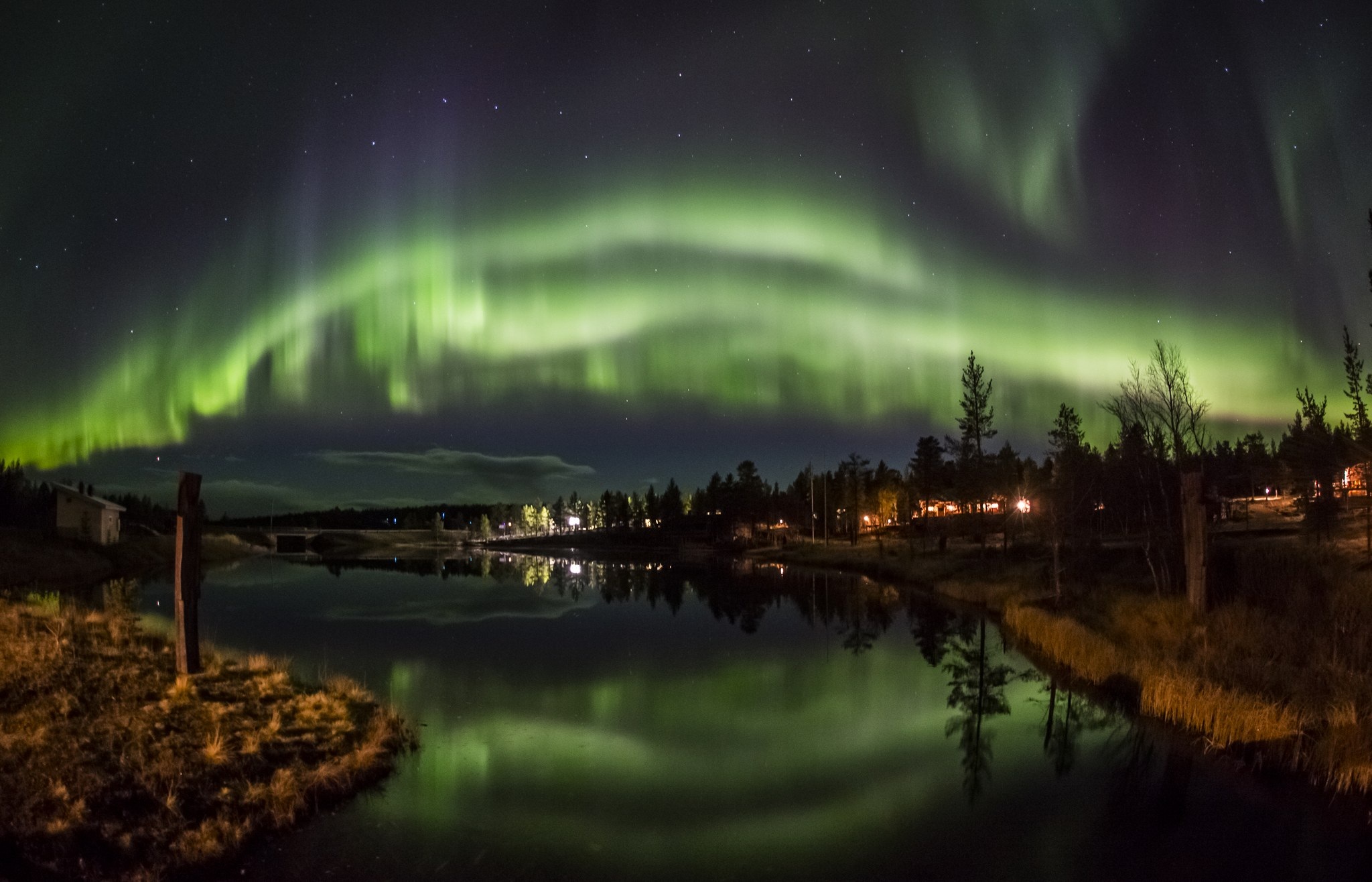 Northern lights reflected in water beside the resort in autumn at Kakslauttanen Arctic Resort, Saariselkä, Finnish Lapland