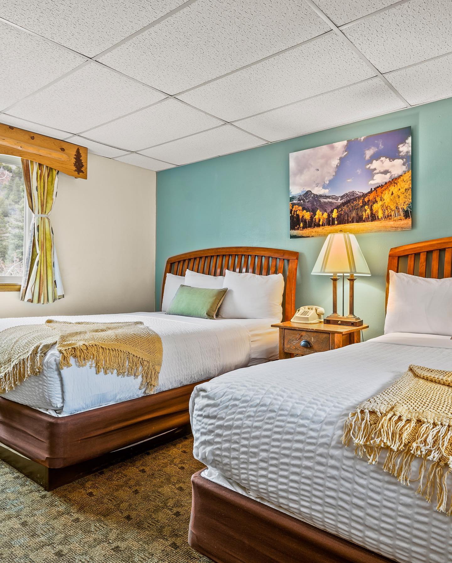Guest room with two queen beds and mountain artwork at Box Canyon Lodge & Hot Springs, Ouray, USA