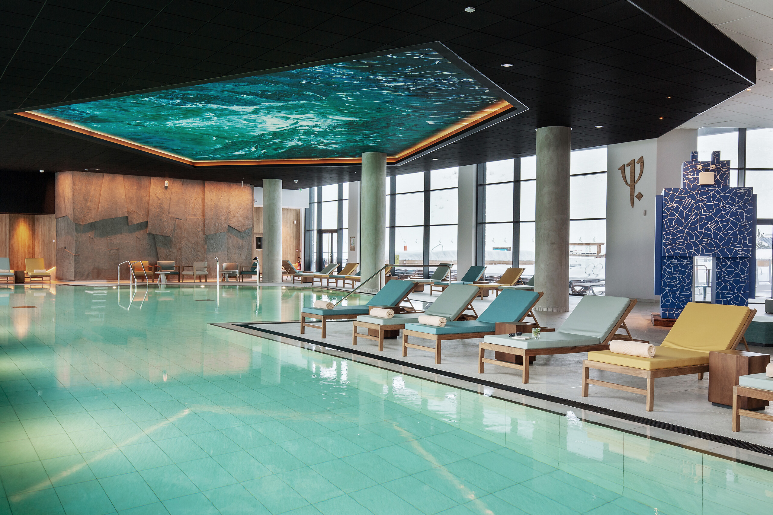 Indoor swimming pool with glass walls, mountain views and turquoise loungers at Club Med Tignes