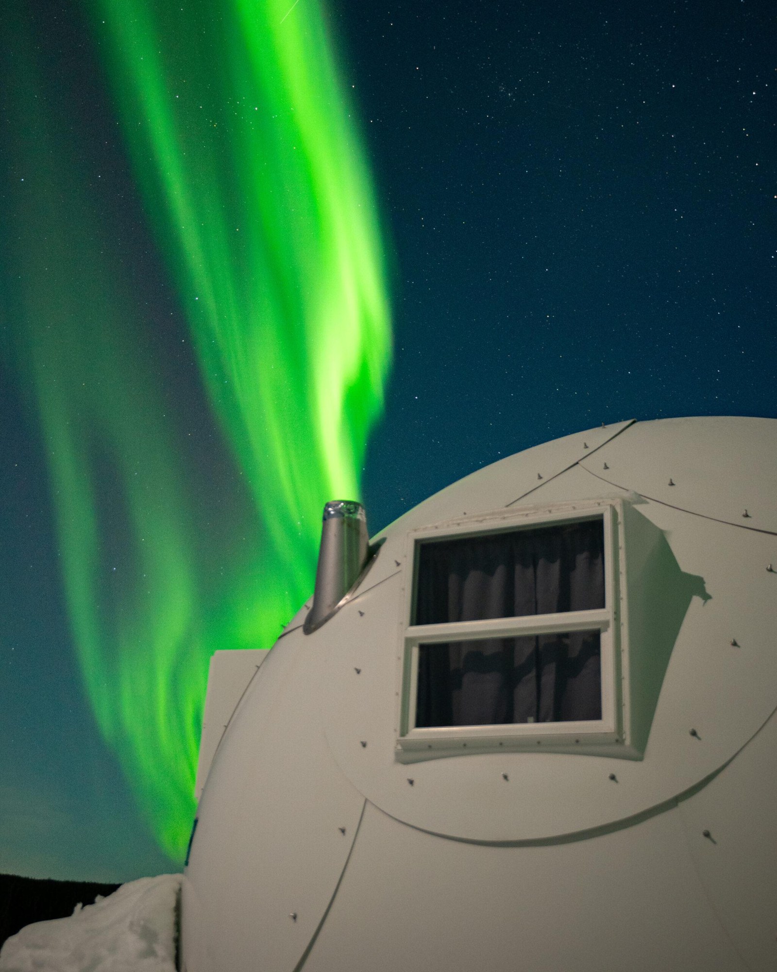 Green northern lights above an igloo in the snowy forest, Borealis Basecamp, Alaska, USA