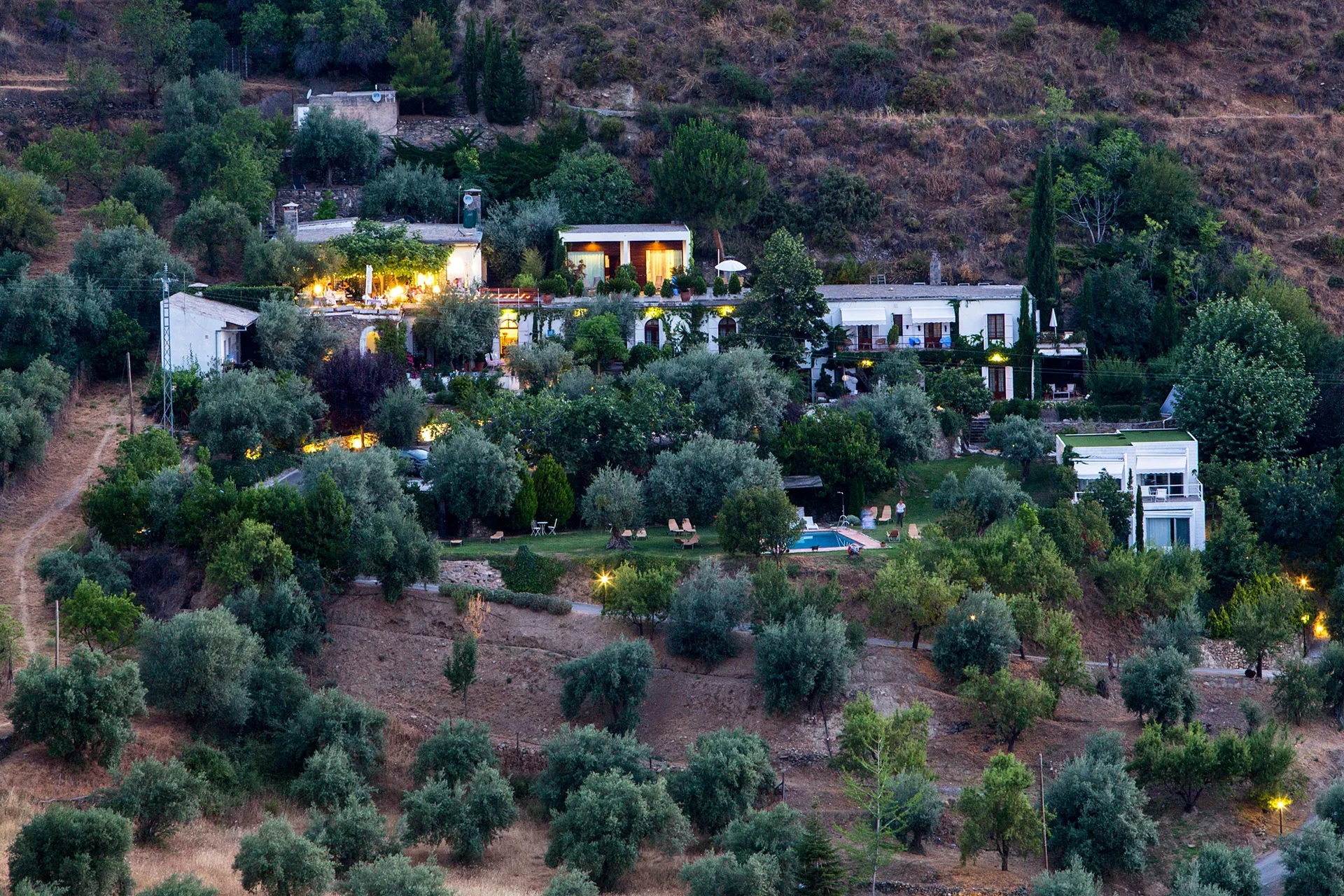 Hillside view of the hotel buildings among olive trees at La Almunia del Valle, Monachil, Spain