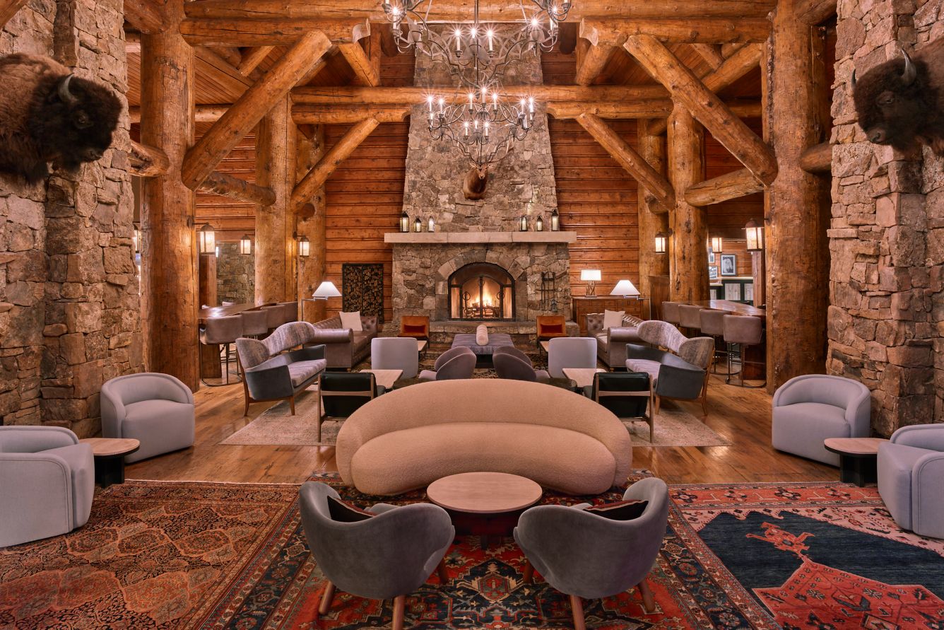 Soaring log beams, stone fireplace and upholstered seating in the Great Room at The Ritz-Carlton, Bachelor Gulch.