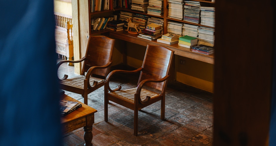 Antique wooden lounge chair beside shelves of books, Casa Palopó, Lake Atitlán, Guatemala