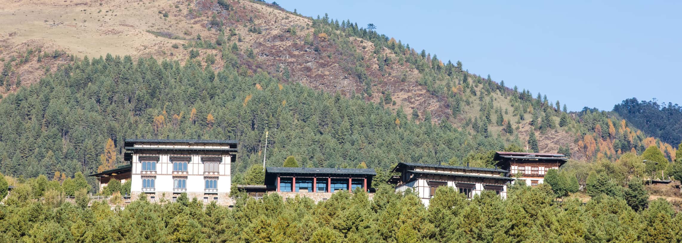 Gangtey Lodge farmhouse exterior on a forested hillside above the Phobjikha Valley, Bhutan