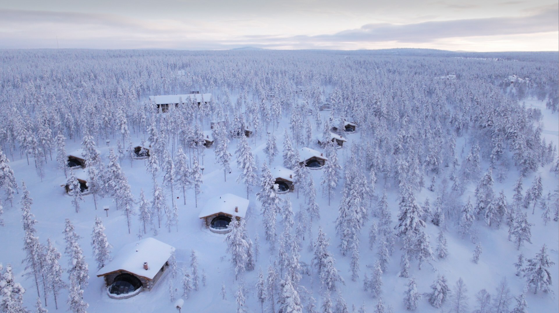 Aerial view of cabins scattered through snow-covered woodland at Kakslauttanen Arctic Resort, Saariselkä, Finnish Lapland