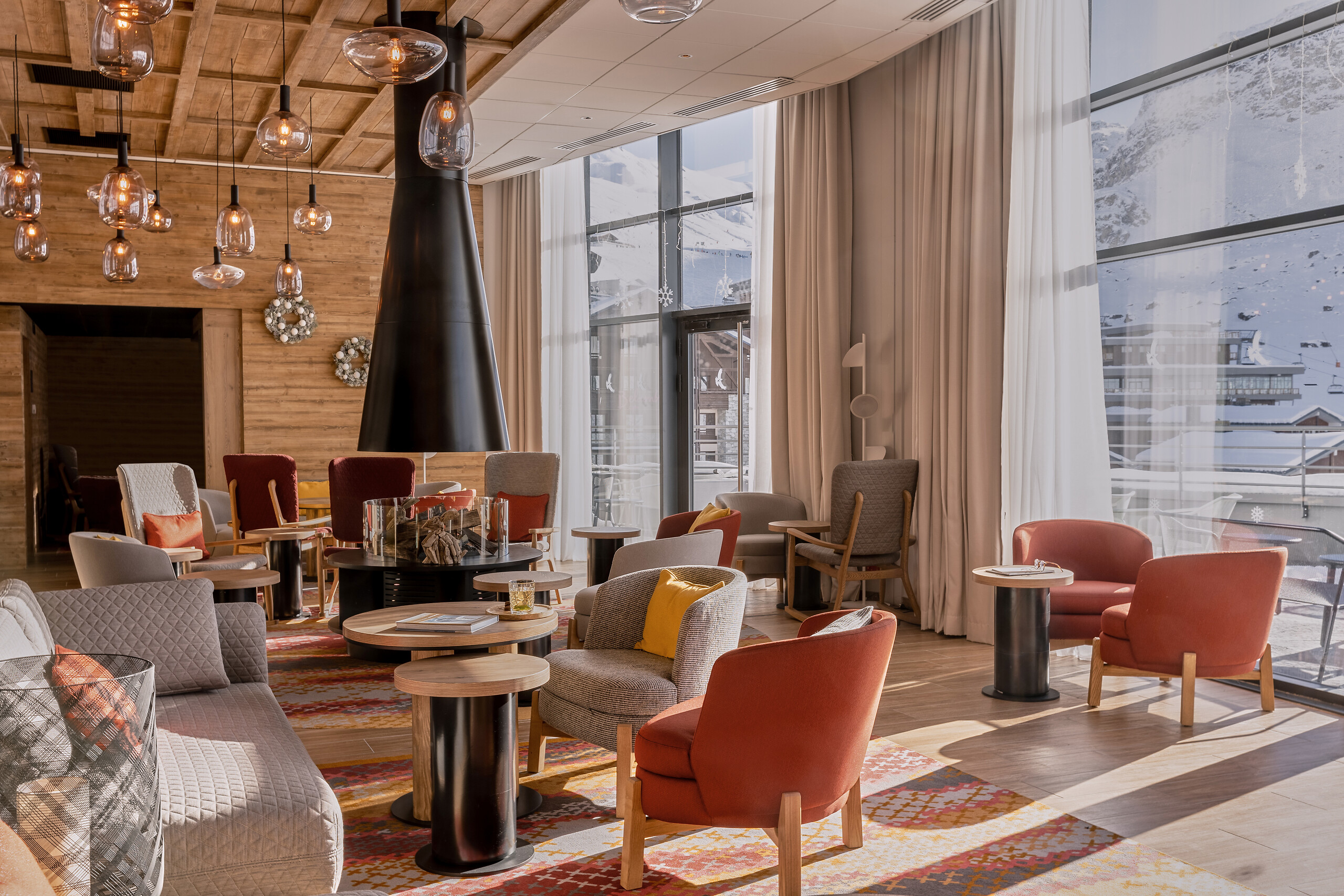 Le Sommet Exclusive Collection lounge with armchairs, a timber ceiling and snowy mountain views at Club Med Tignes