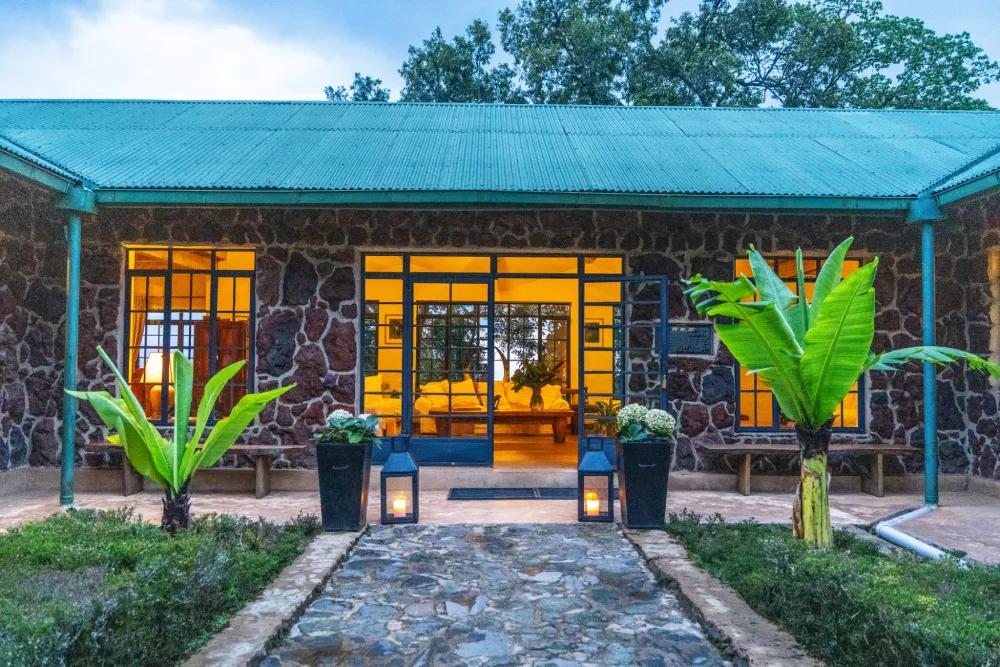 Stone lodge exterior with a welcoming illuminated entrance, Clouds Mountain Gorilla Lodge, Bwindi Impenetrable National Park, Uganda