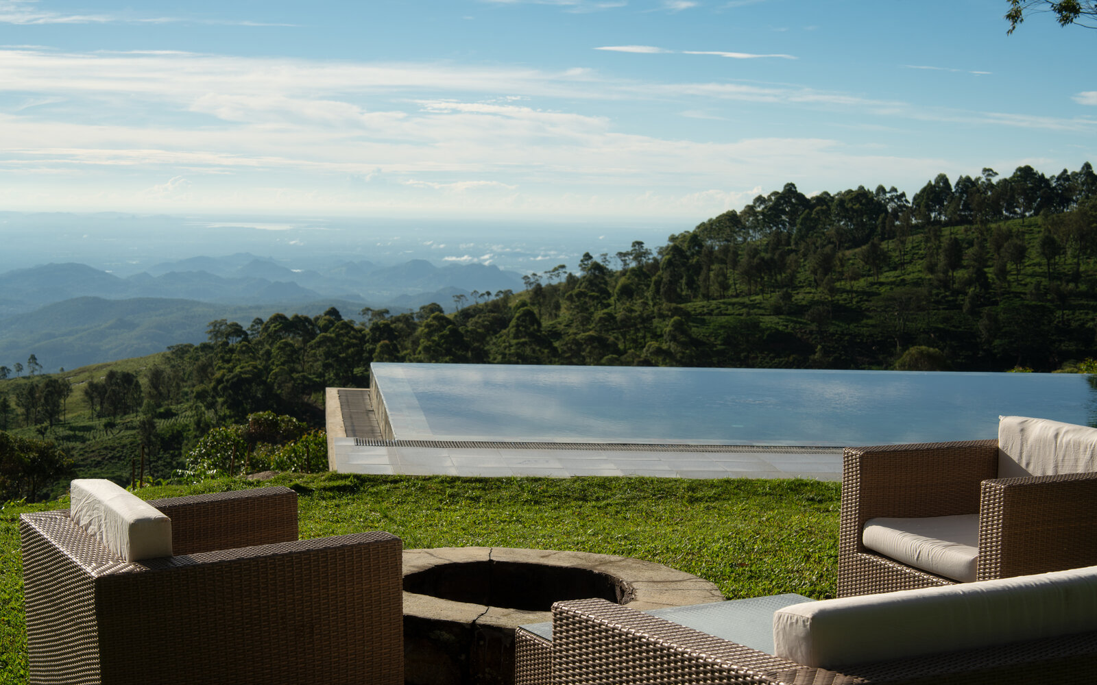 Infinity pool and wicker terrace chairs overlooking the hills at Thotalagala, Sri Lanka