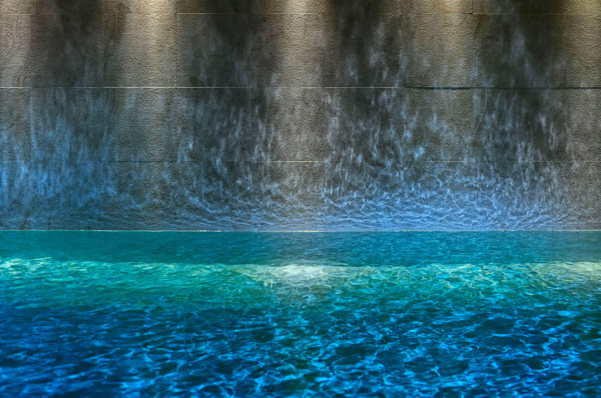 Indoor spa swimming pool with stone waterfall wall, Guarda Golf Hotel & Residences, Crans-Montana, Switzerland