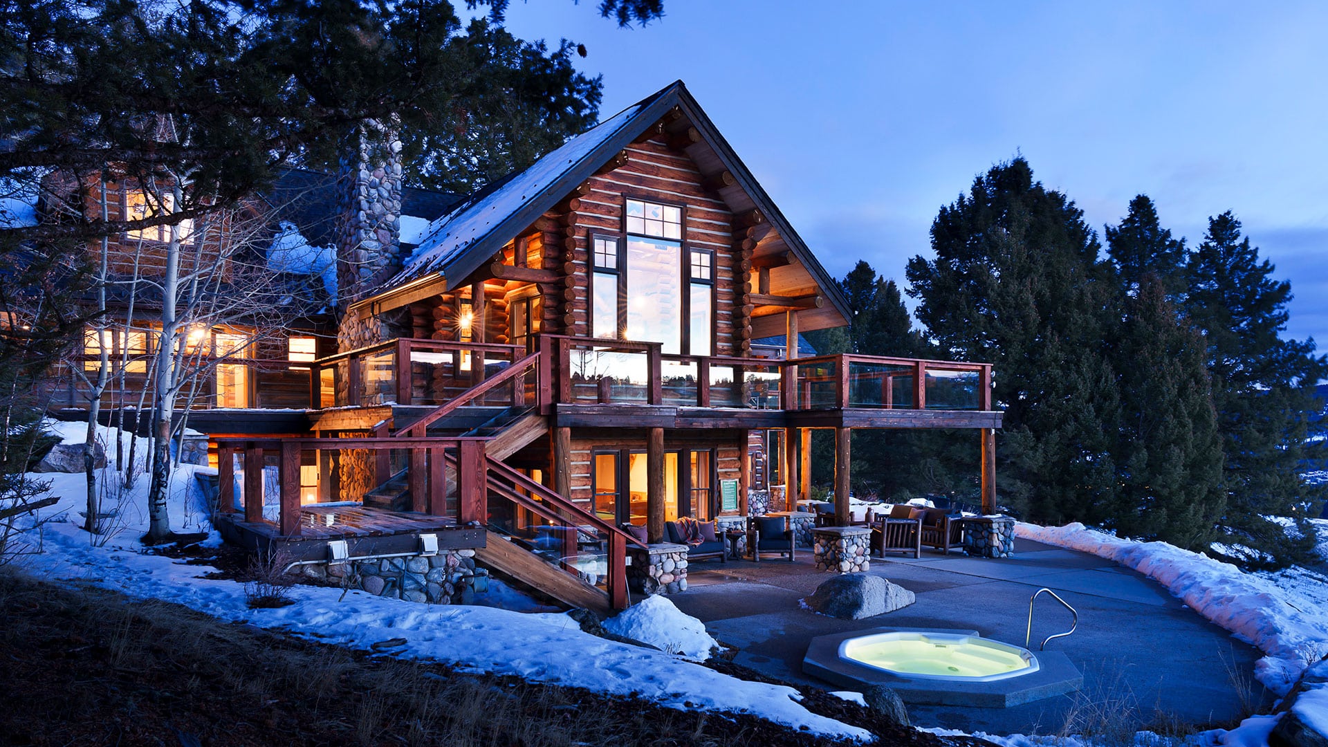 Snow-covered Ridgetop cabin exterior at dusk with outdoor hot tub, Lone Mountain Ranch, Big Sky, USA