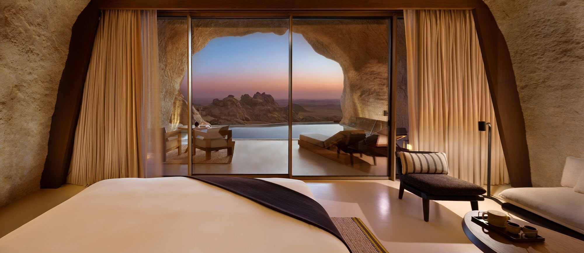 A Mountain Cave Suite interior at Desert Rock, carved into the rock with a glass wall opening onto a private pool