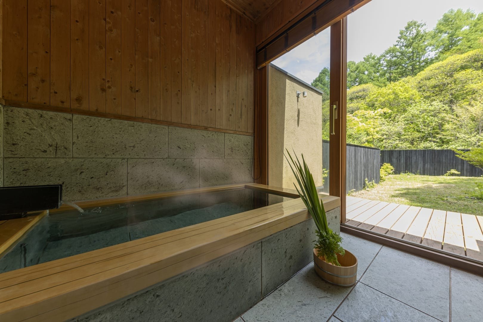 Wooden guest-room soaking tub beside an open window facing a green hillside, Hoshinoya Karuizawa