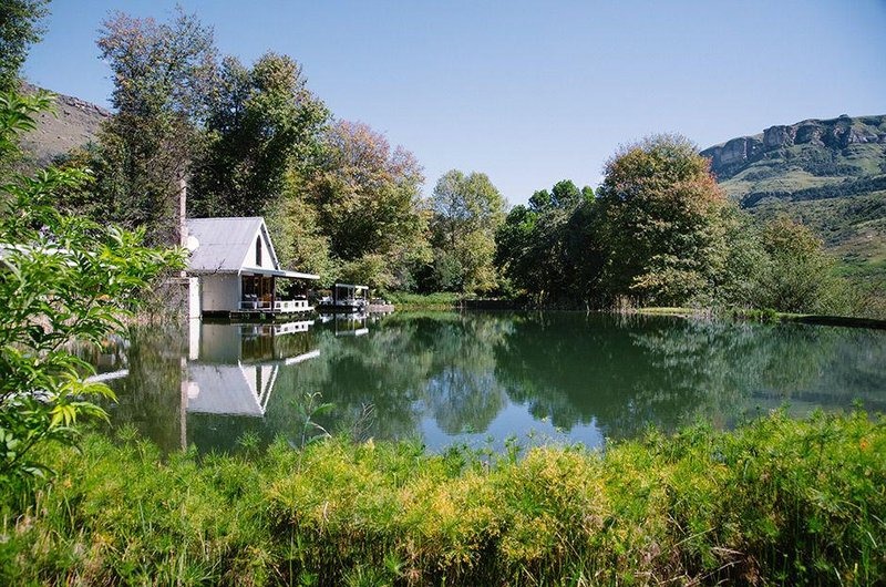 Farmhouse exterior reflected in a pond beneath the mountains, Cleopatra Mountain Farmhouse, Drakensberg, KwaZulu-Natal, South Africa