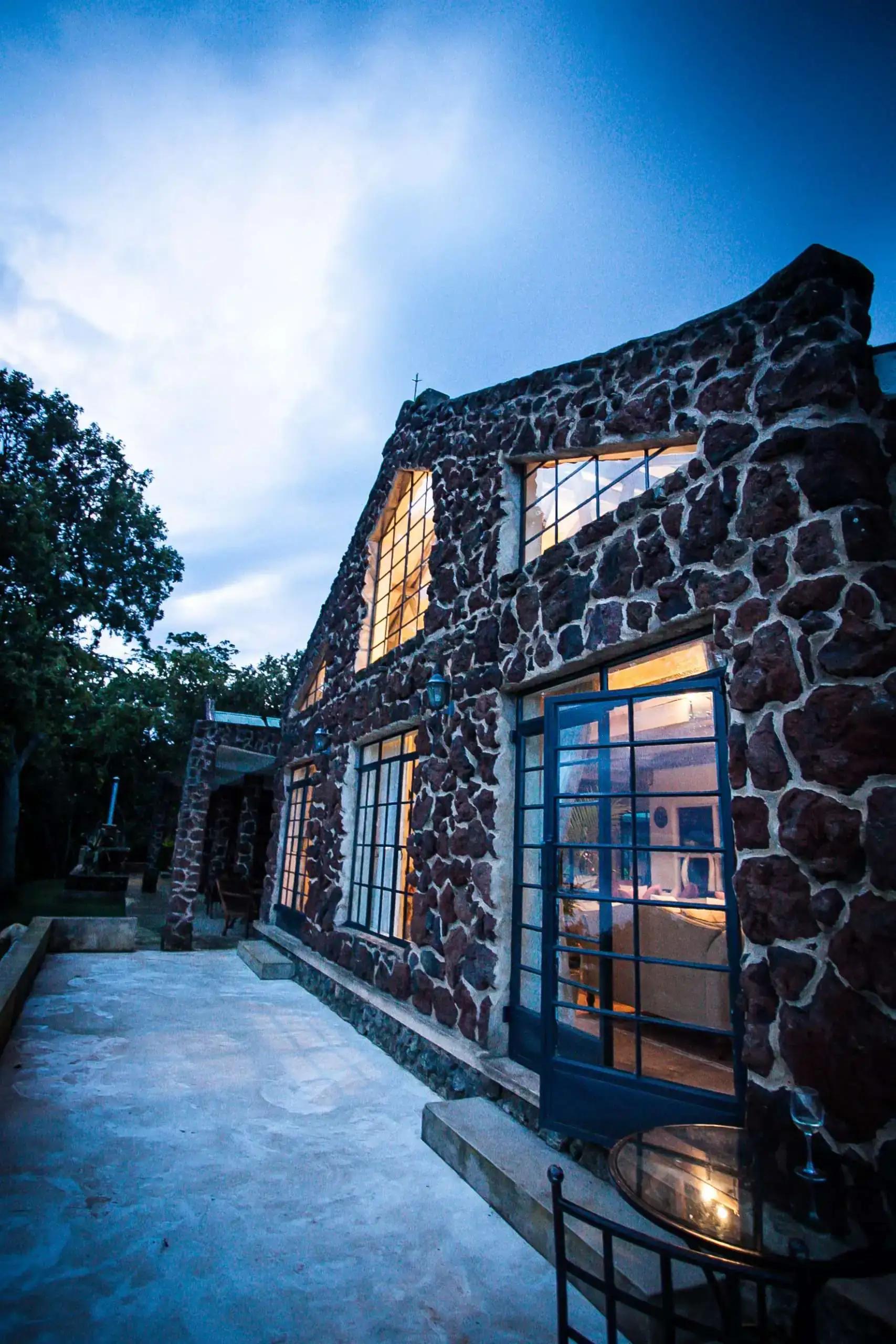 Stone cottage exterior beside a paved terrace at dusk, Clouds Mountain Gorilla Lodge, Bwindi Impenetrable National Park, Uganda
