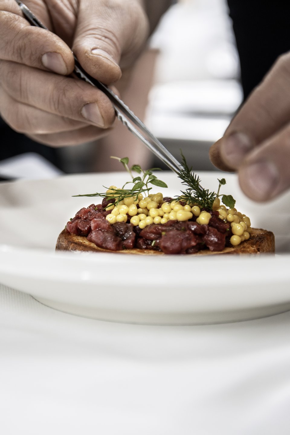 Chef garnishing a dish at Alpin Panorama Hotel Hubertus, Olang, Italy