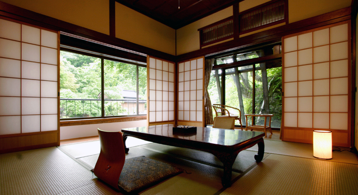 Japanese-style tatami room with a low table, chairs, sliding screens and green views at Takaragawa Onsen Osenkaku, Gunma