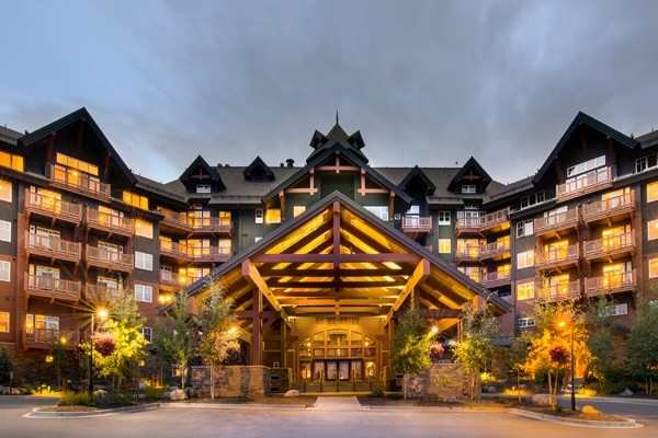 Illuminated entrance and mountain-style exterior of One Ski Hill Place at dusk.