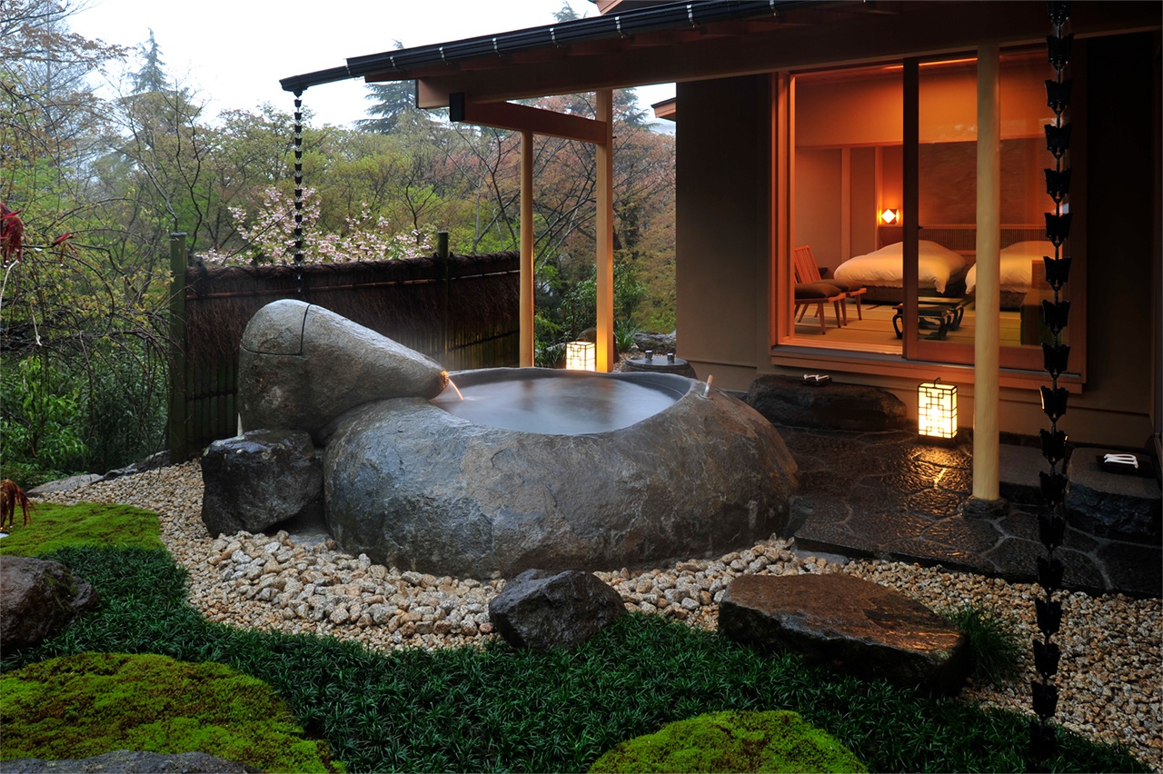 Outdoor stone bath beside a warmly lit room at Gora Kadan, Hakone, Japan