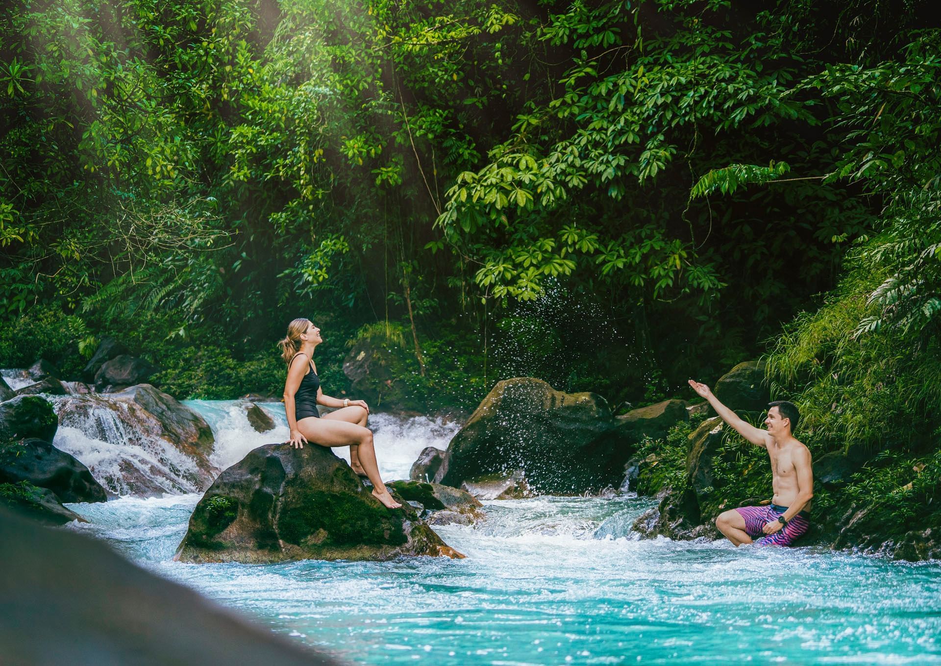 Guests relaxing beside turquoise river cascades in the rainforest, Hideaway Rio Celeste, Tenorio, Costa Rica