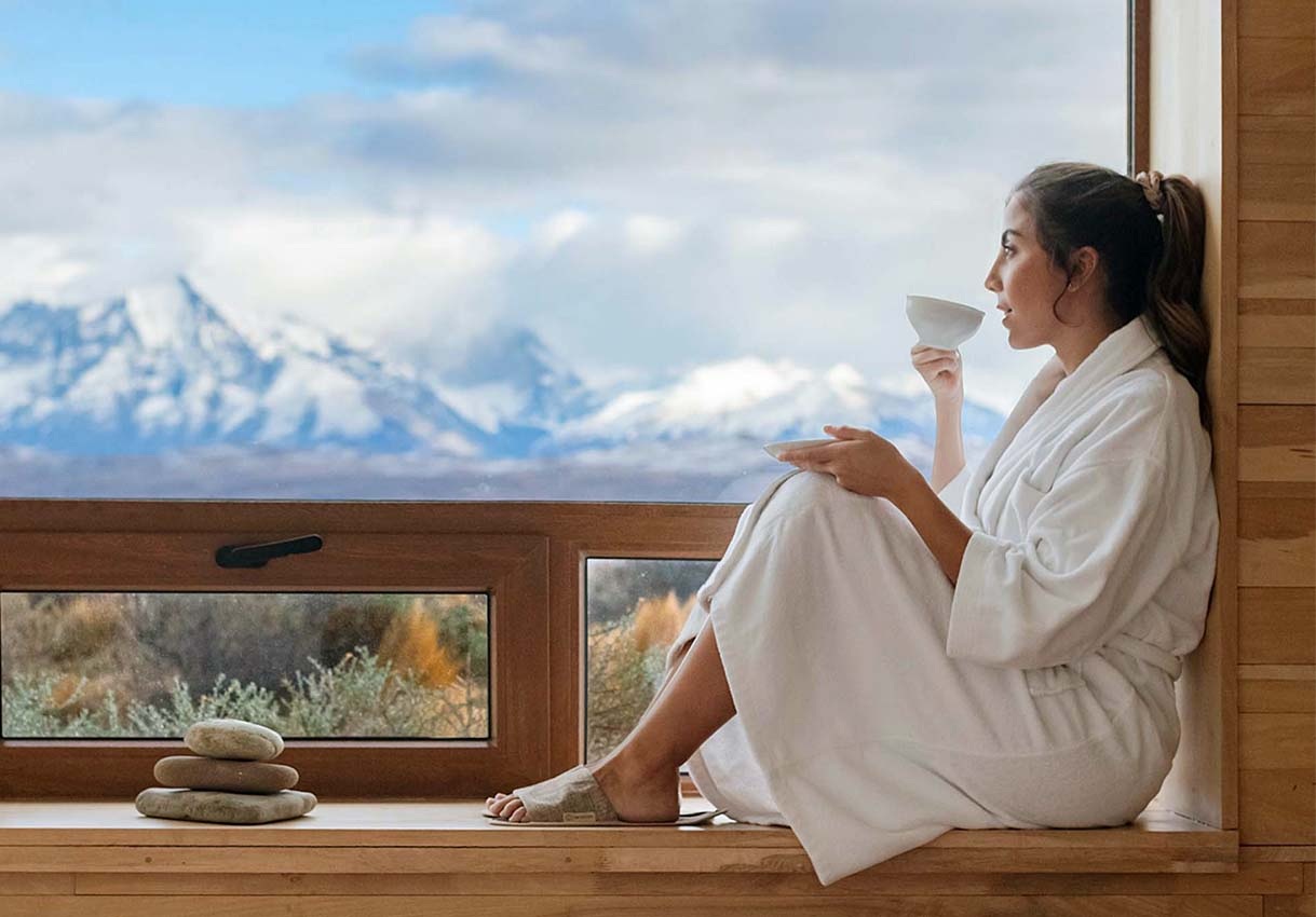 Guest seated by a window facing the mountains at Tierra Patagonia, Torres del Paine, Chile