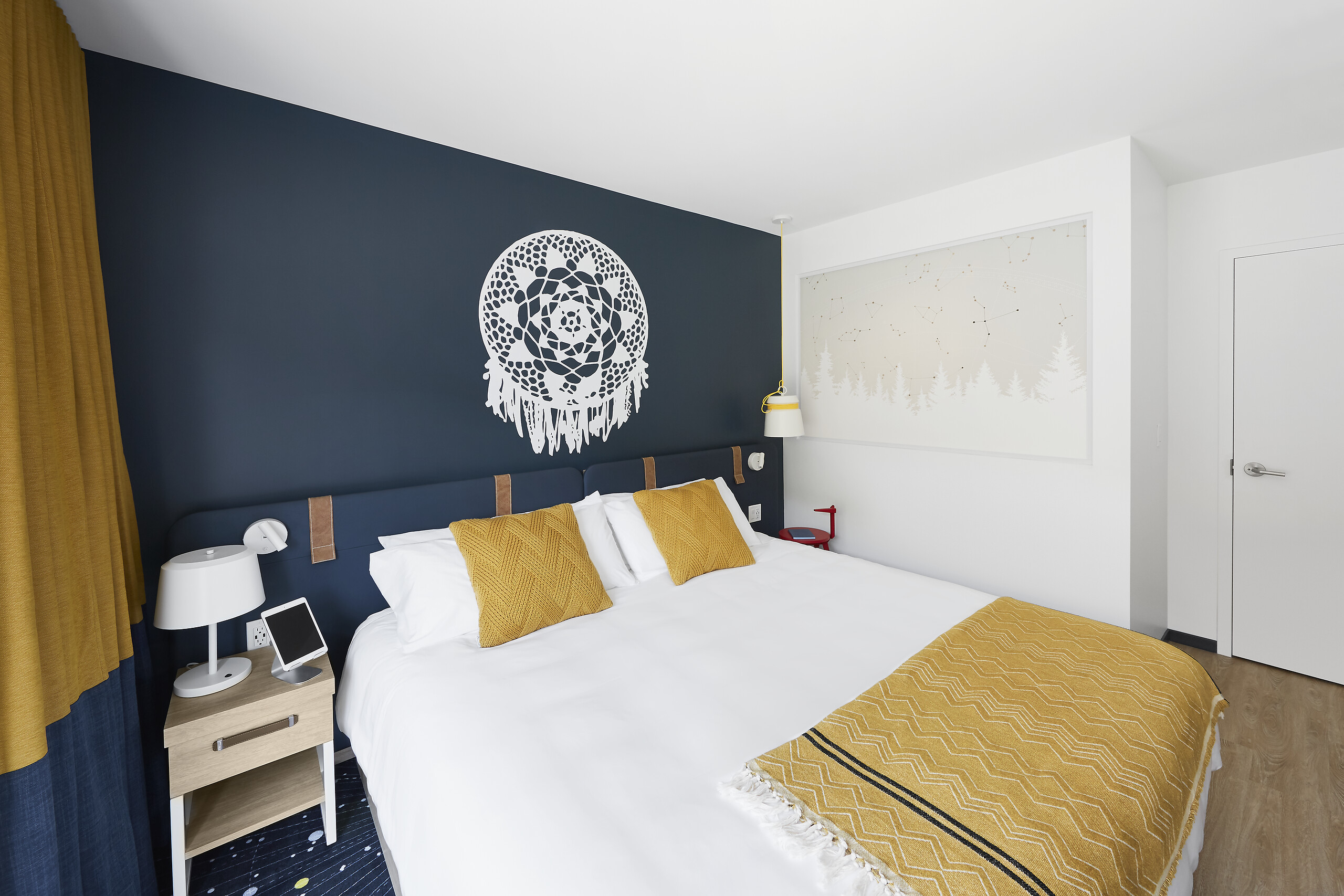 Superior room with a king-size bed, yellow cushions and a dream-catcher headboard at Club Med Québec Charlevoix