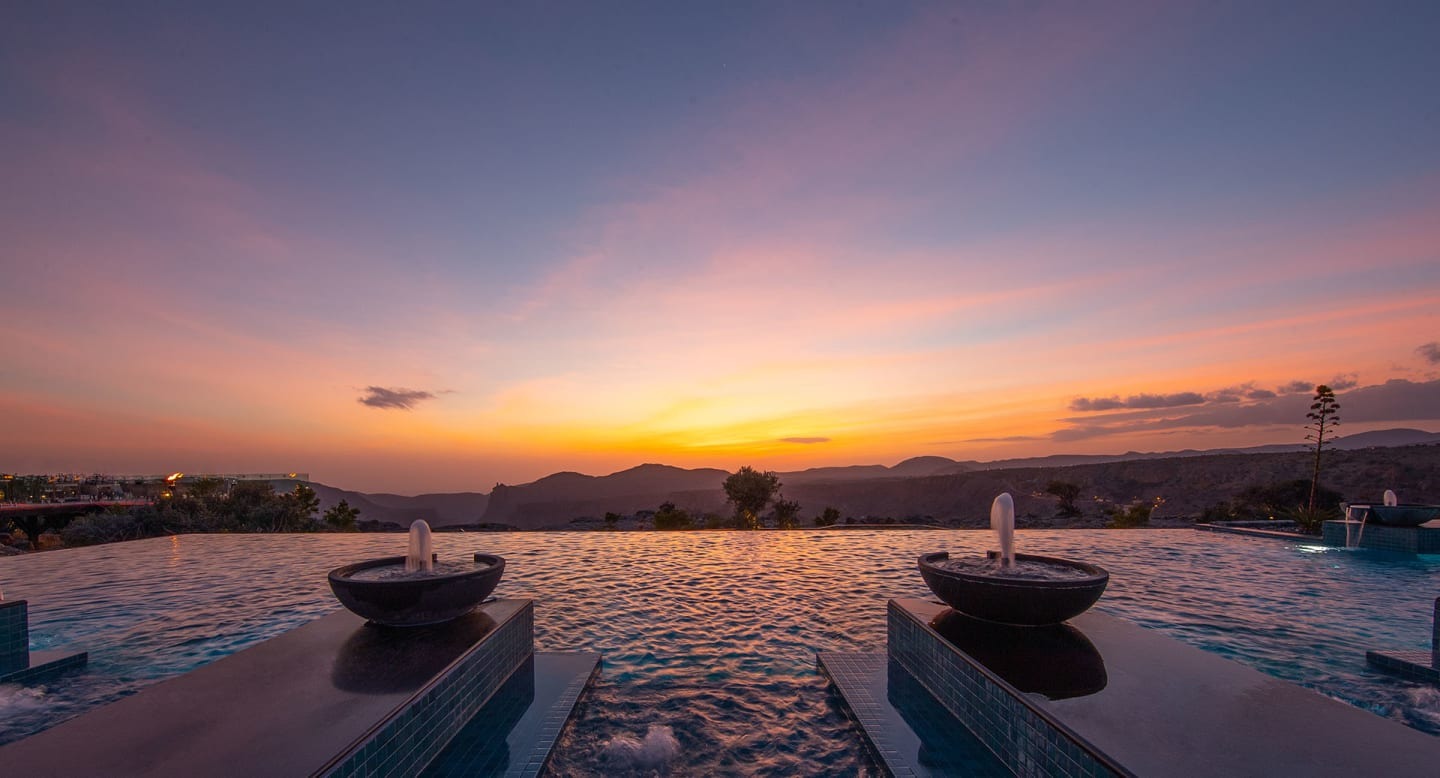 Resort pool and fire bowls at sunset, Anantara Al Jabal Al Akhdar, Jebel Akhdar, Oman