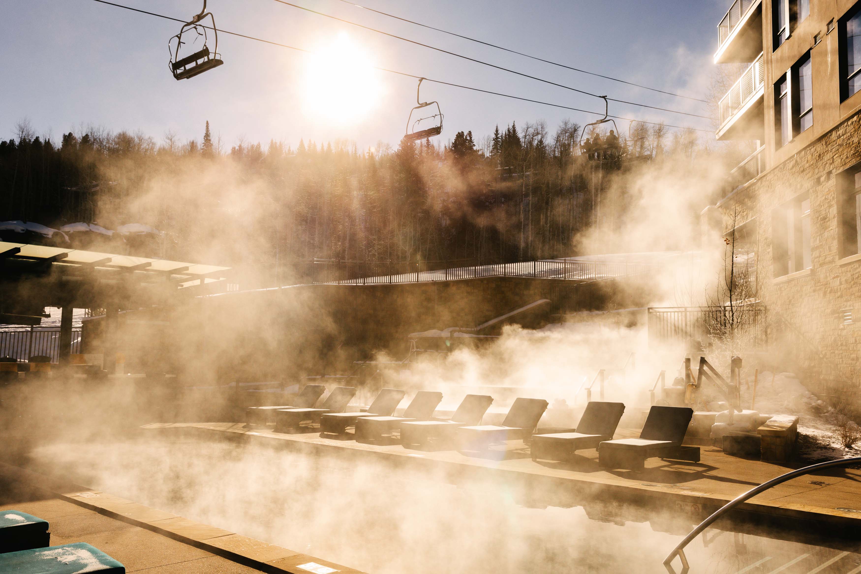 Steam rising from Viceroy Snowmass’s heated outdoor pool beneath the chairlift on a winter morning.