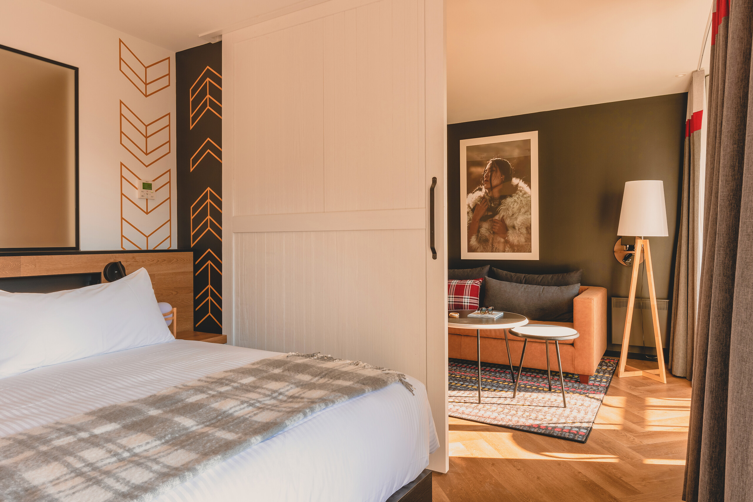 Exclusive Collection river-view suite with a king-size bed, patterned wall and lounge seating at Club Med Québec Charlevoix