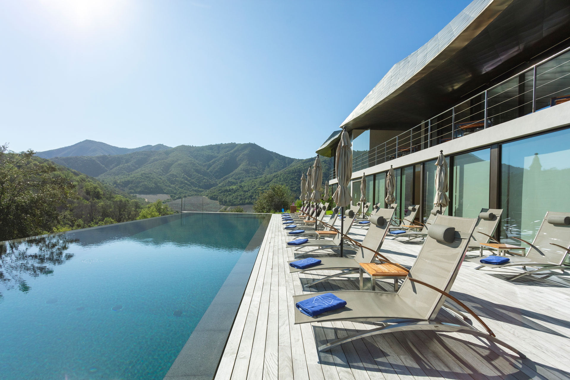 VIK infinity pool beside the glass-fronted hotel with mountains beyond