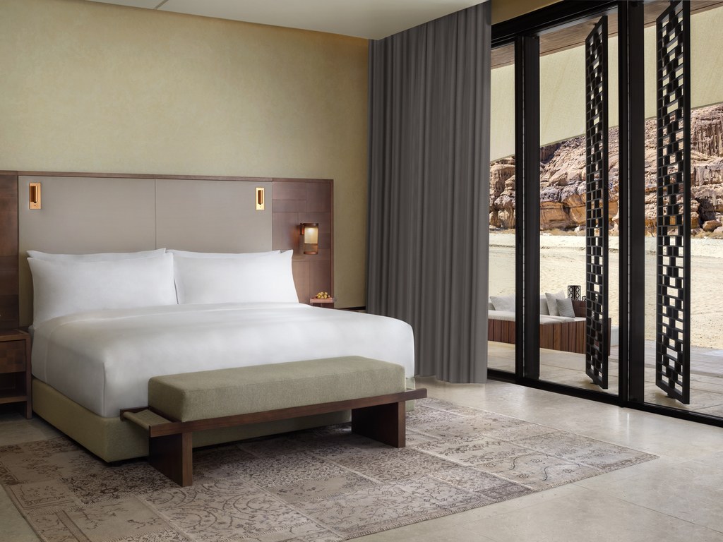 Villa bedroom with a king bed and patterned screens opening toward the desert at Banyan Tree AlUla.