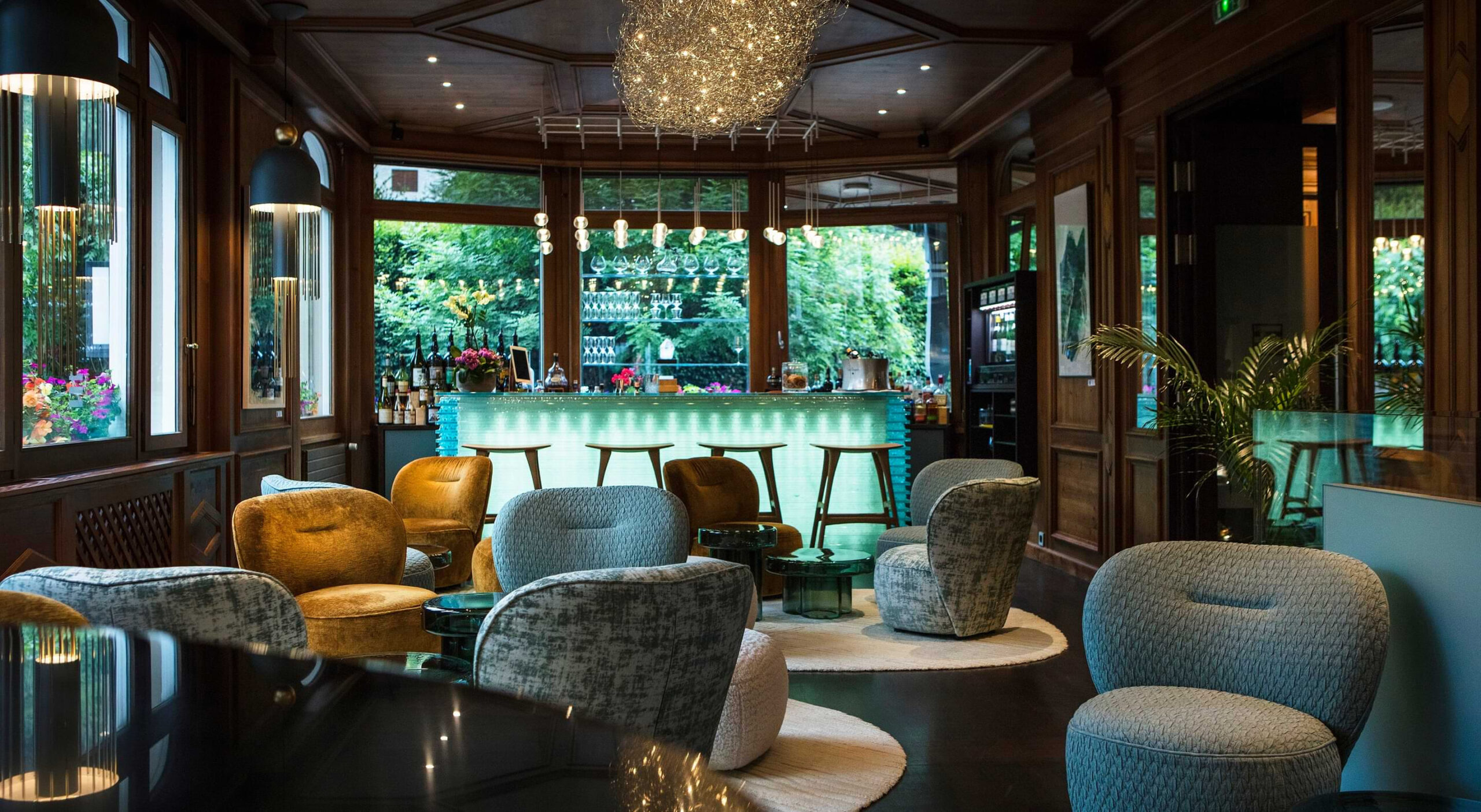 Quartz Bar lounge with cushioned chairs, chandelier and illuminated bar, Le Hameau Albert 1er, Chamonix, France