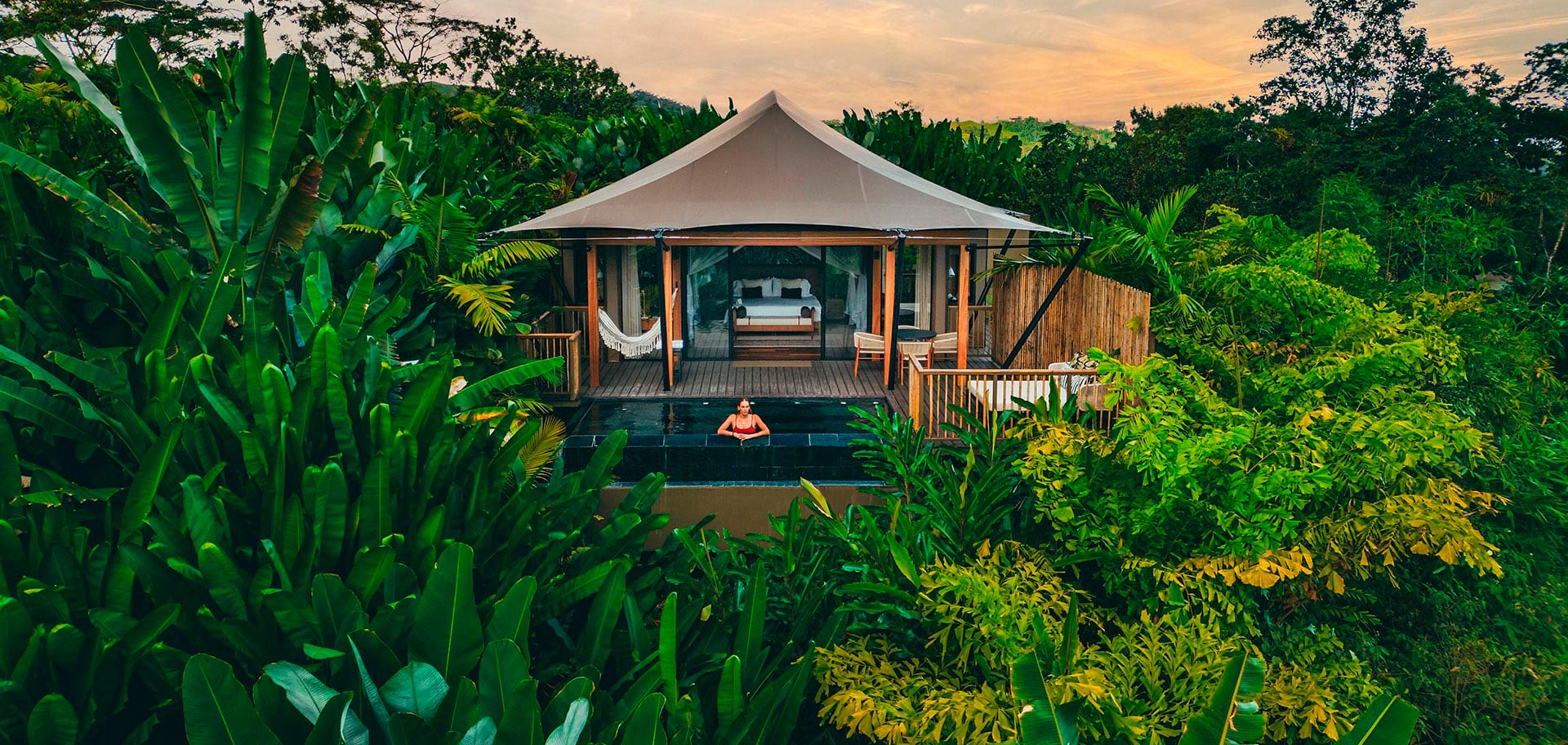 Tented villa exterior surrounded by tropical greenery at sunset, Nayara Tented Camp, Arenal, Costa Rica