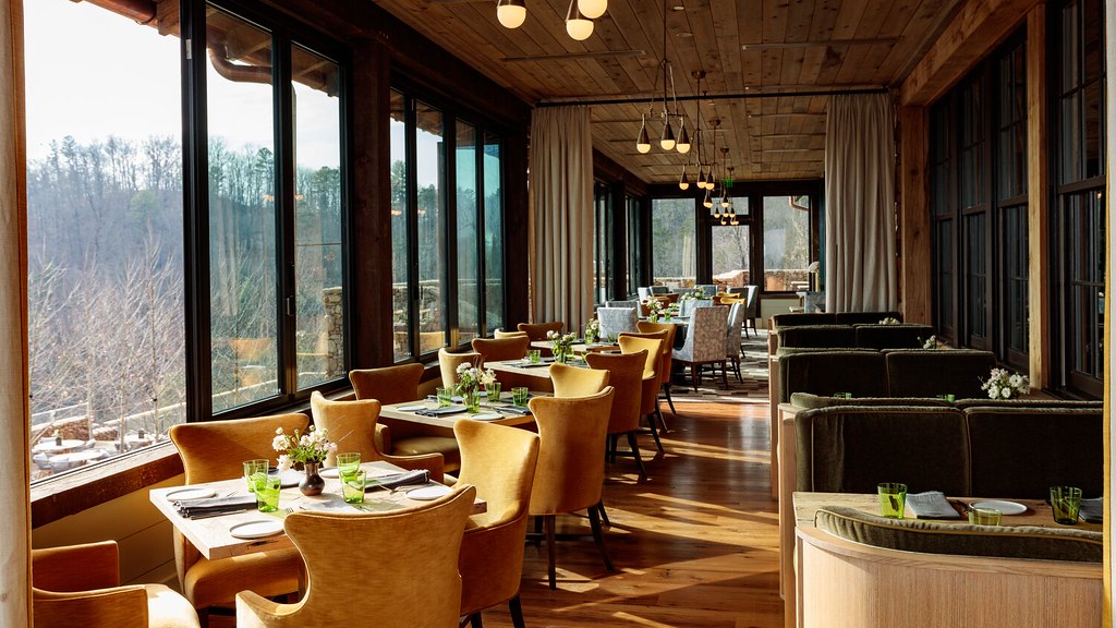 Three Sisters dining room with golden chairs and tall windows facing the trees at Blackberry Mountain, Walland, USA