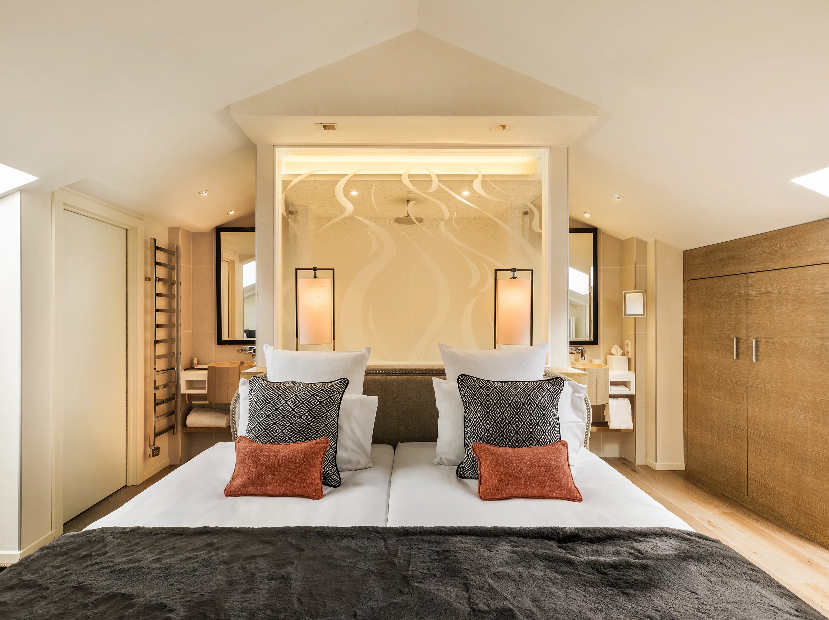 Hotel bedroom with a double bed, patterned headboard and timber finishes