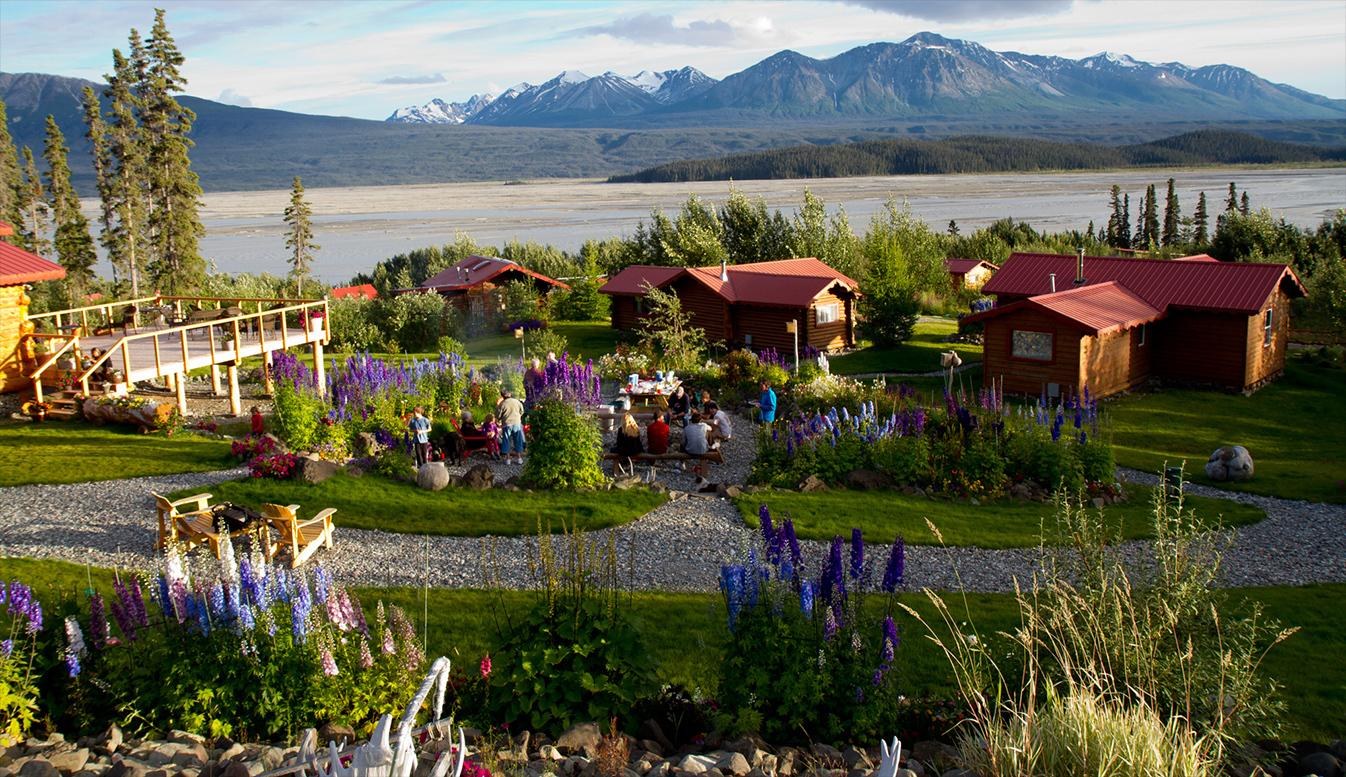 Log cabins and wildflower gardens above the Chitina River, Ultima Thule Lodge, Alaska, USA