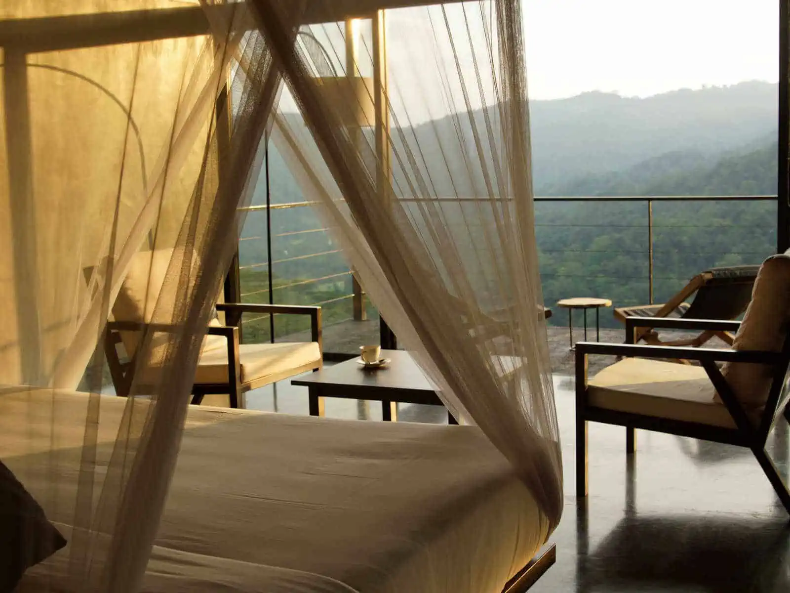Chalet interior with a canopy bed and open views of the mountain valley at Santani Wellness Resort & Spa, Sri Lanka