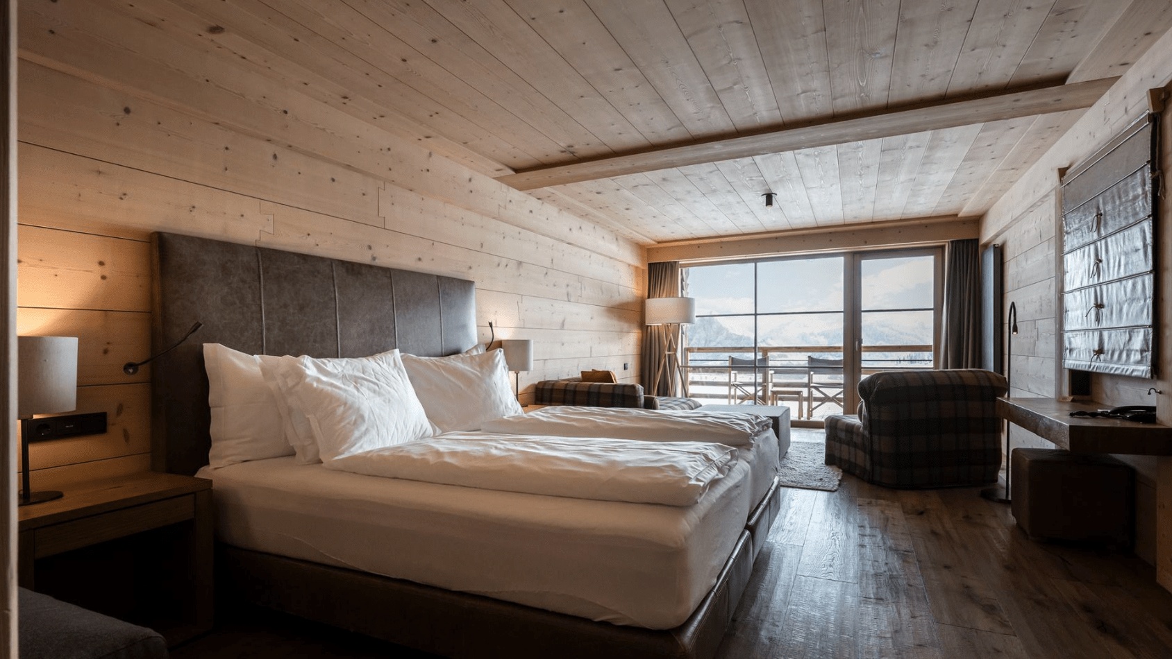 Wood-panelled guest room with a double bed and large windows at Adler Mountain Lodge, Alpe di Siusi (Seiser Alm), Italy