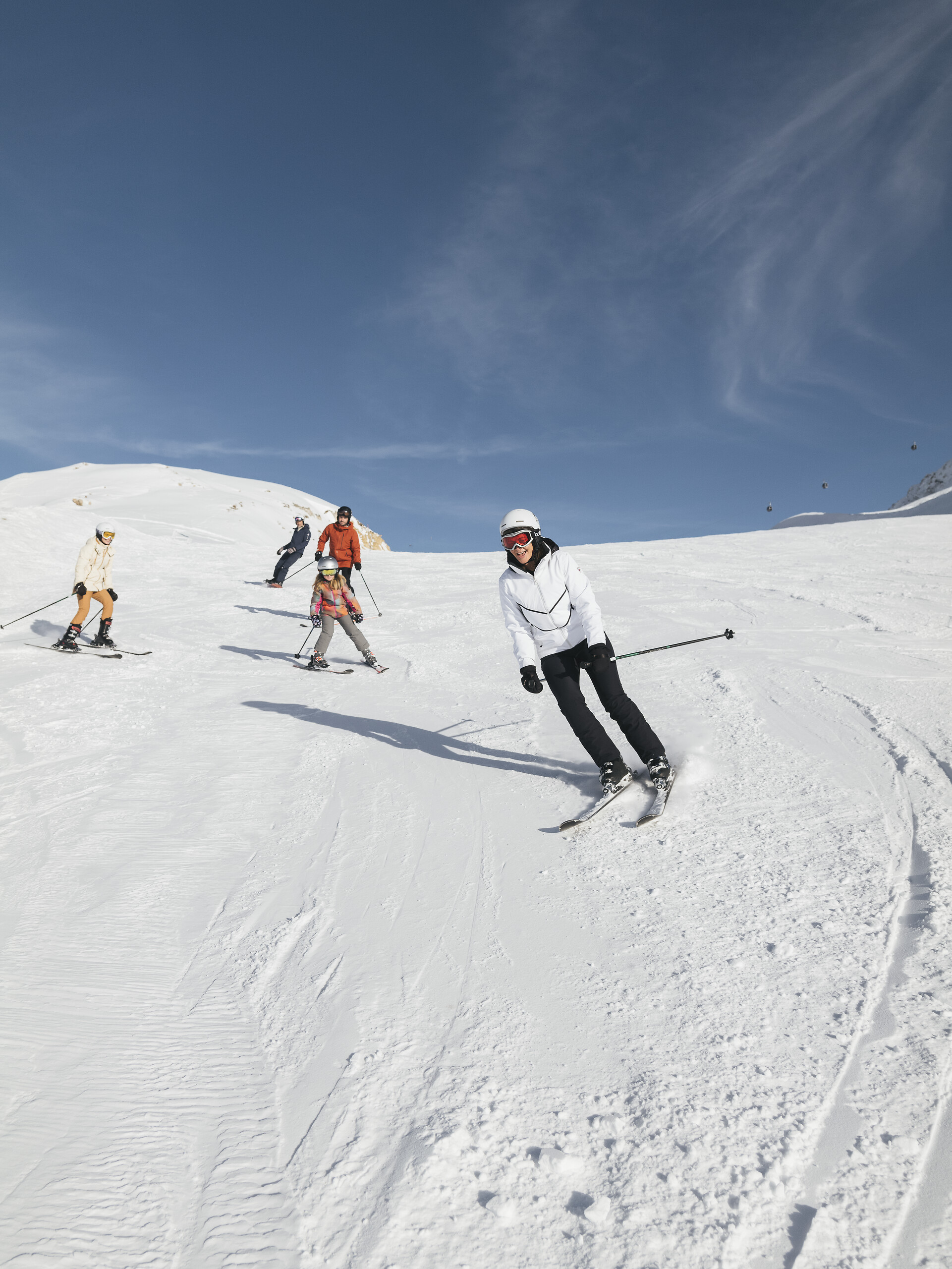 Family skiing together on a groomed snowy slope, from Club Med Tignes