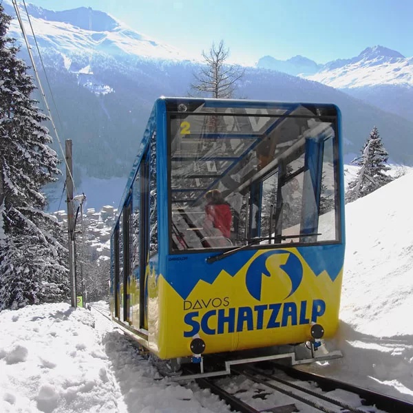 Blue Schatzalp funicular carriage on tracks in a snowy mountain landscape, Davos, Switzerland