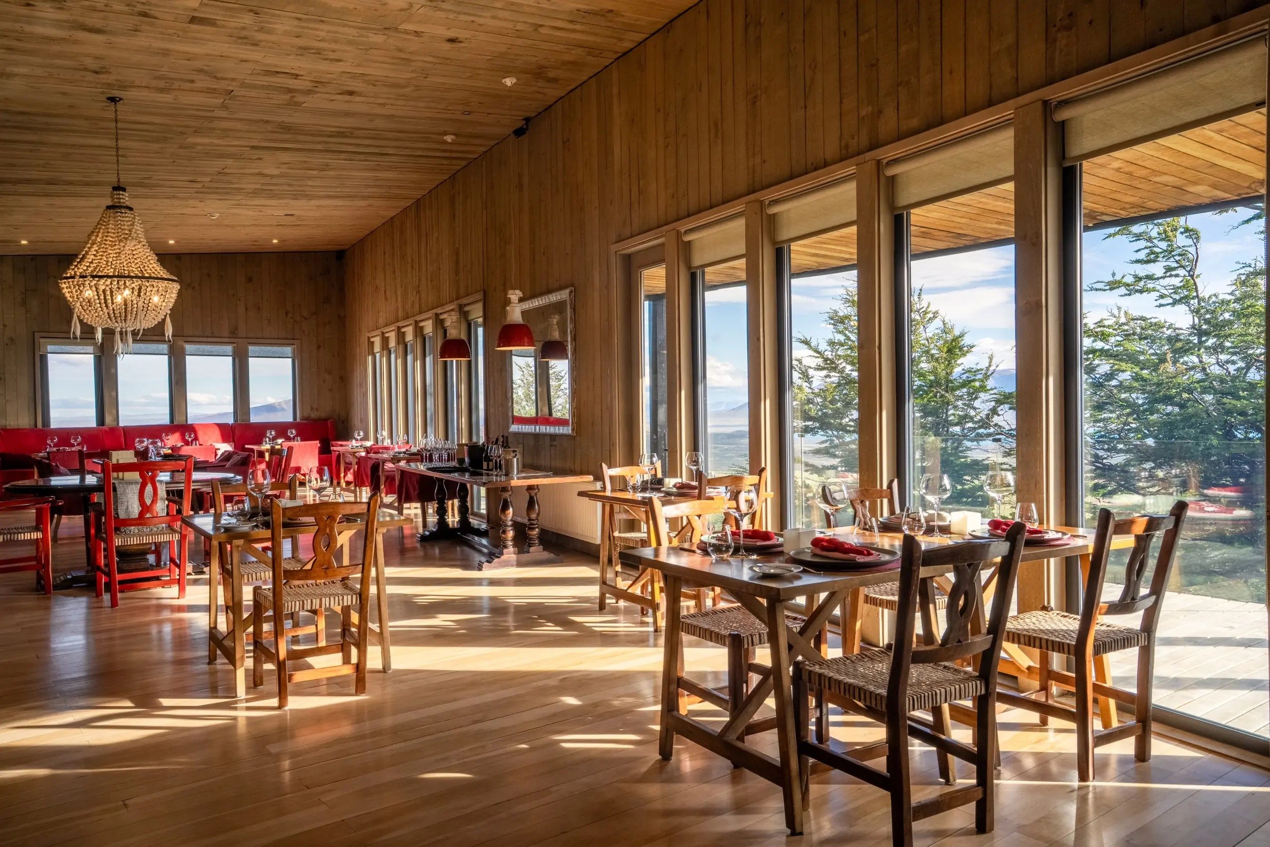 Main lodge dining room with timber walls, set tables and large windows overlooking the landscape, Awasi Patagonia