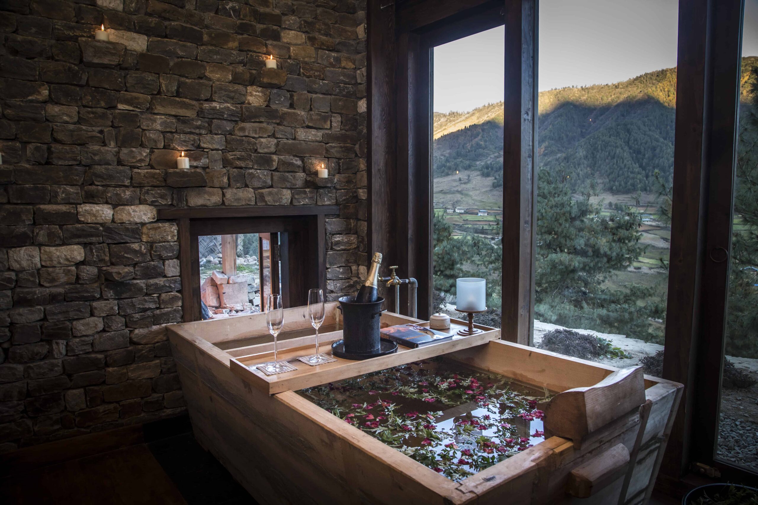 Traditional wooden hot stone spa bath in Gangtey Lodge’s stone-walled bath house, beside a fire and valley-facing window