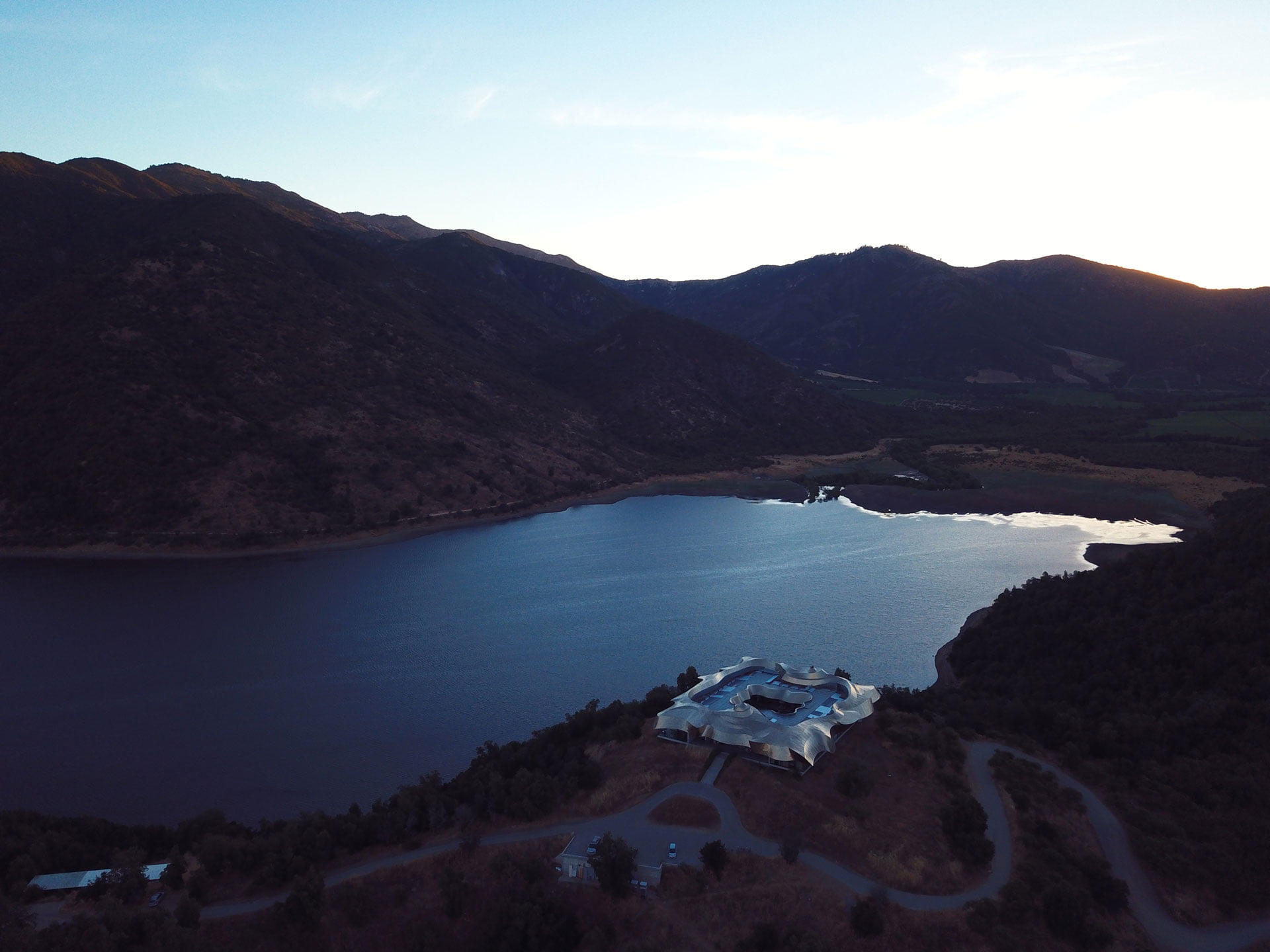 Aerial view of a hotel beside a lake and dark hills at VIK Chile, Millahue Valley, Chile